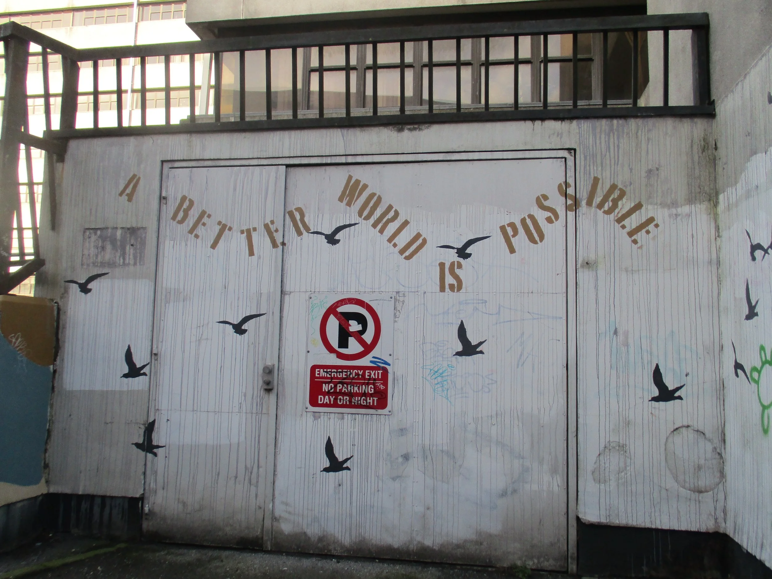 graffiti that says "A better world is possible" with silhouettes of flying birds