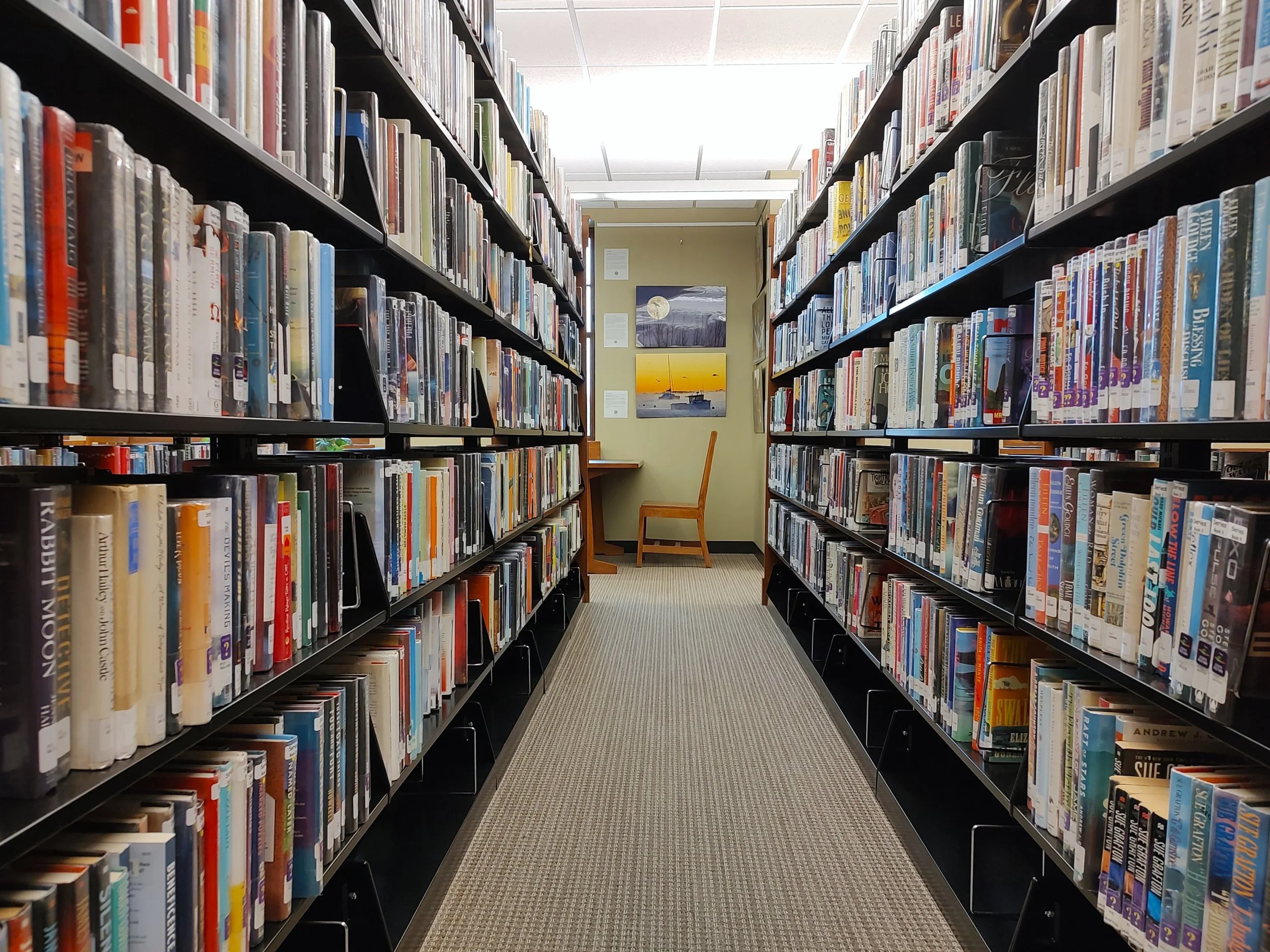 library stacks leading to an empty desk chair