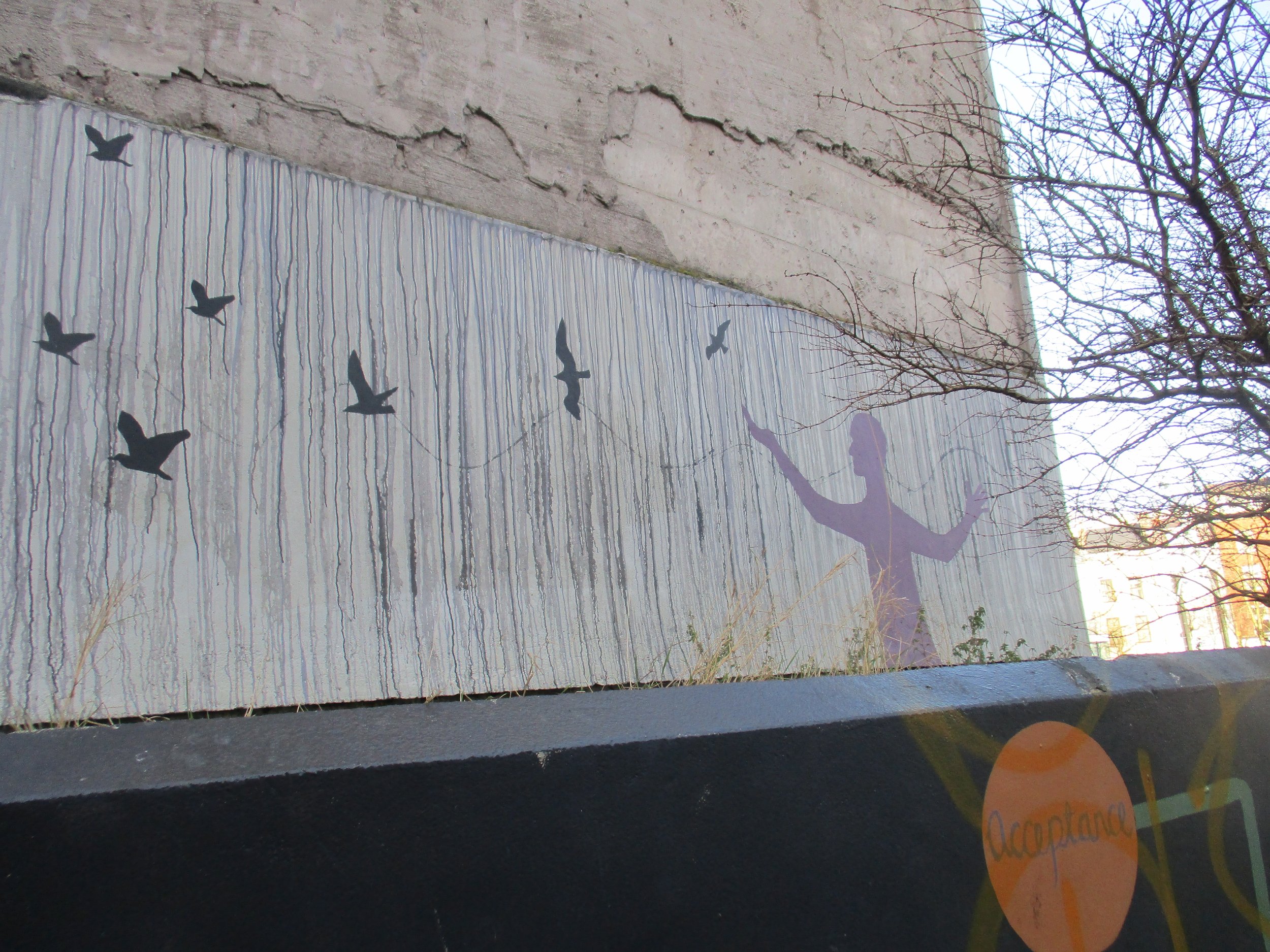 purple silhouette of a person reaching out to black silhouette birds that are flying away.