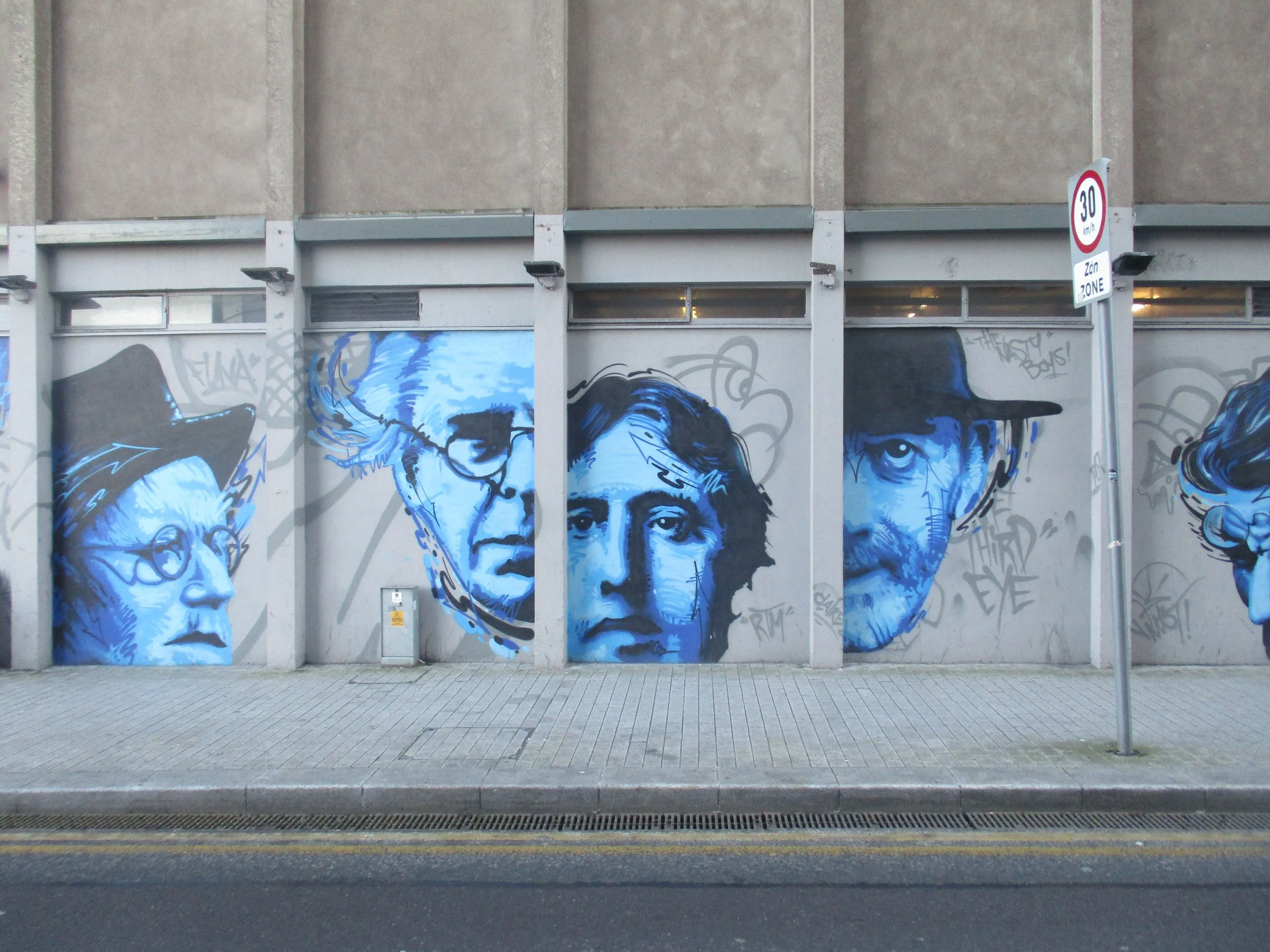 a series of realistic male faces in blue paint on a wall