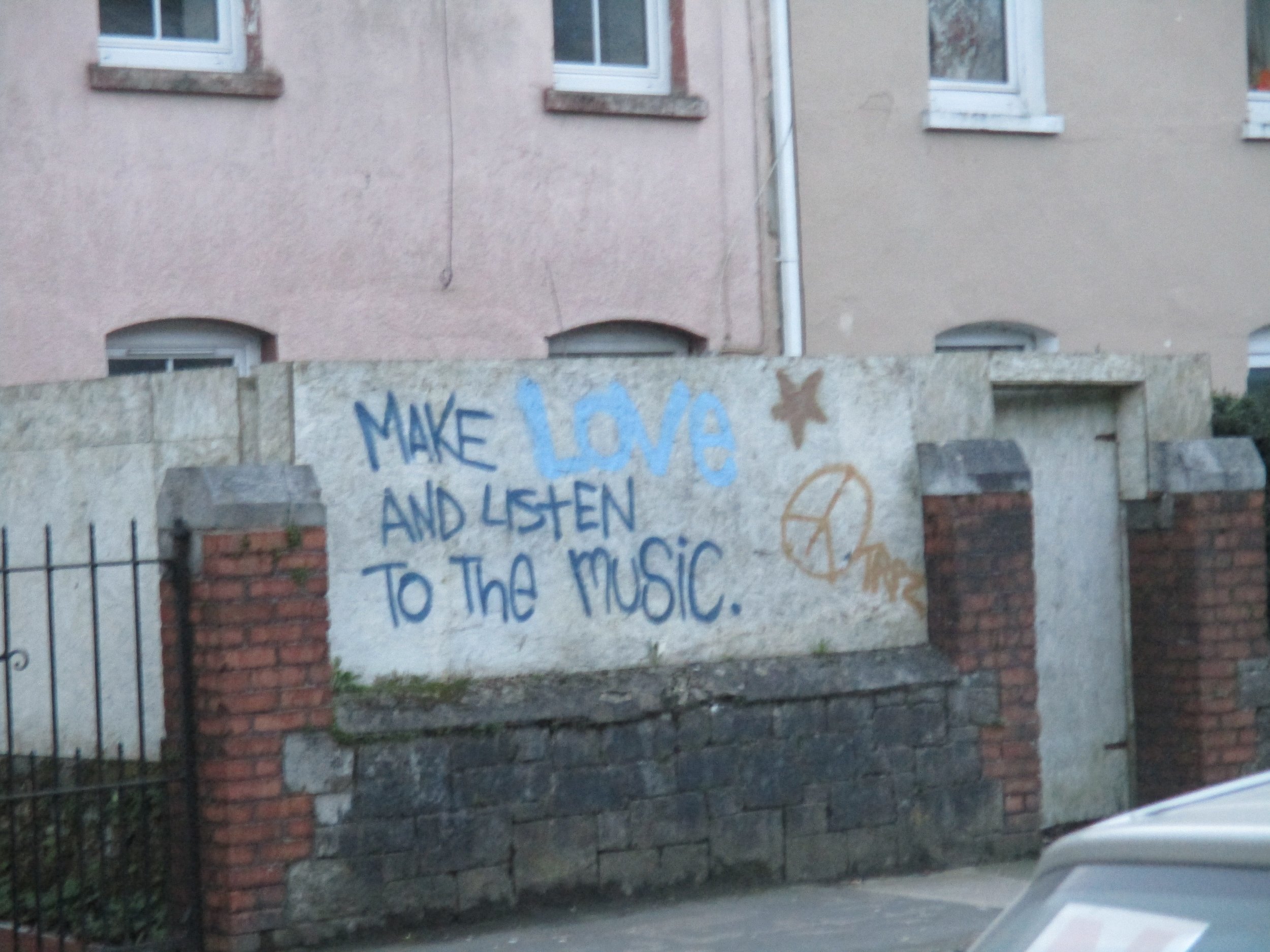 graffiti that says "make love and listen to the music" with a peace sign