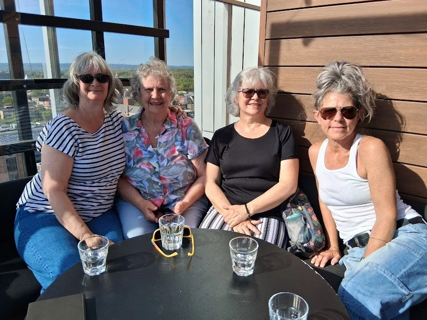 4 women sitting at a restaurant table, smiling for the camera.