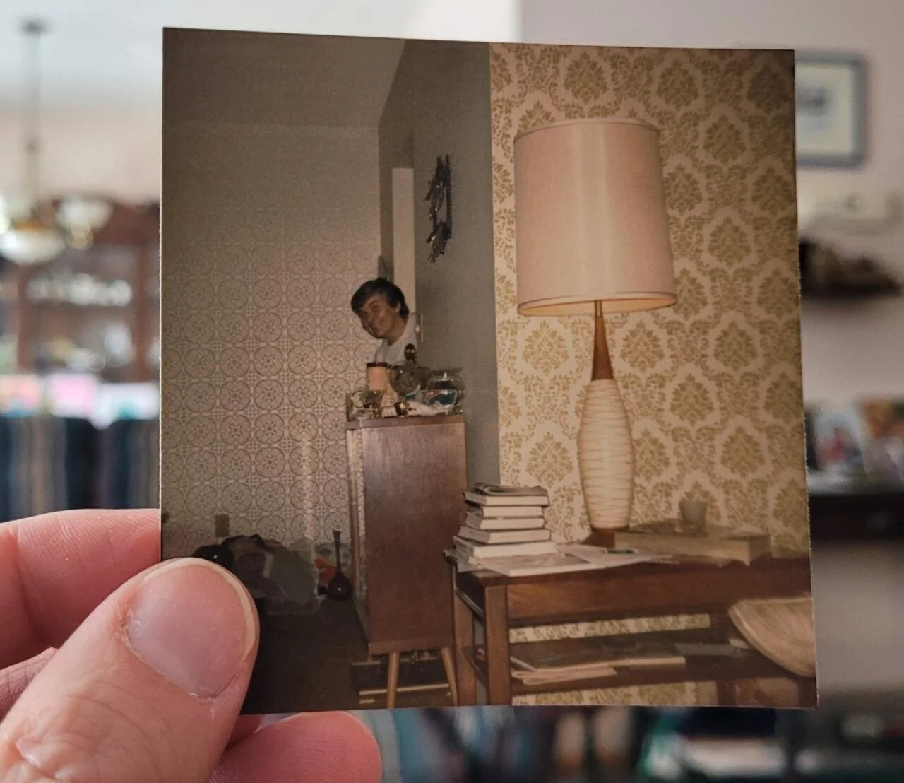 a hand holding an old photo of a woman.