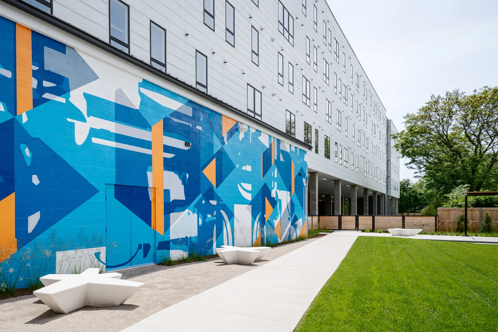 Mural wall along the courtyard lawn with white concrete benches.