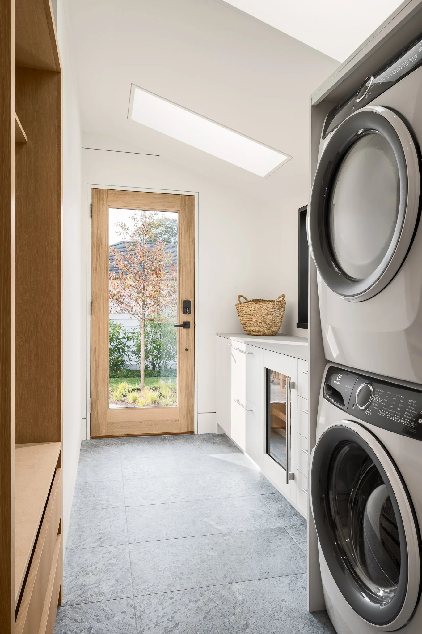 Mudroom and laundry with stacked machines, a coat rack and a glass-paned door.