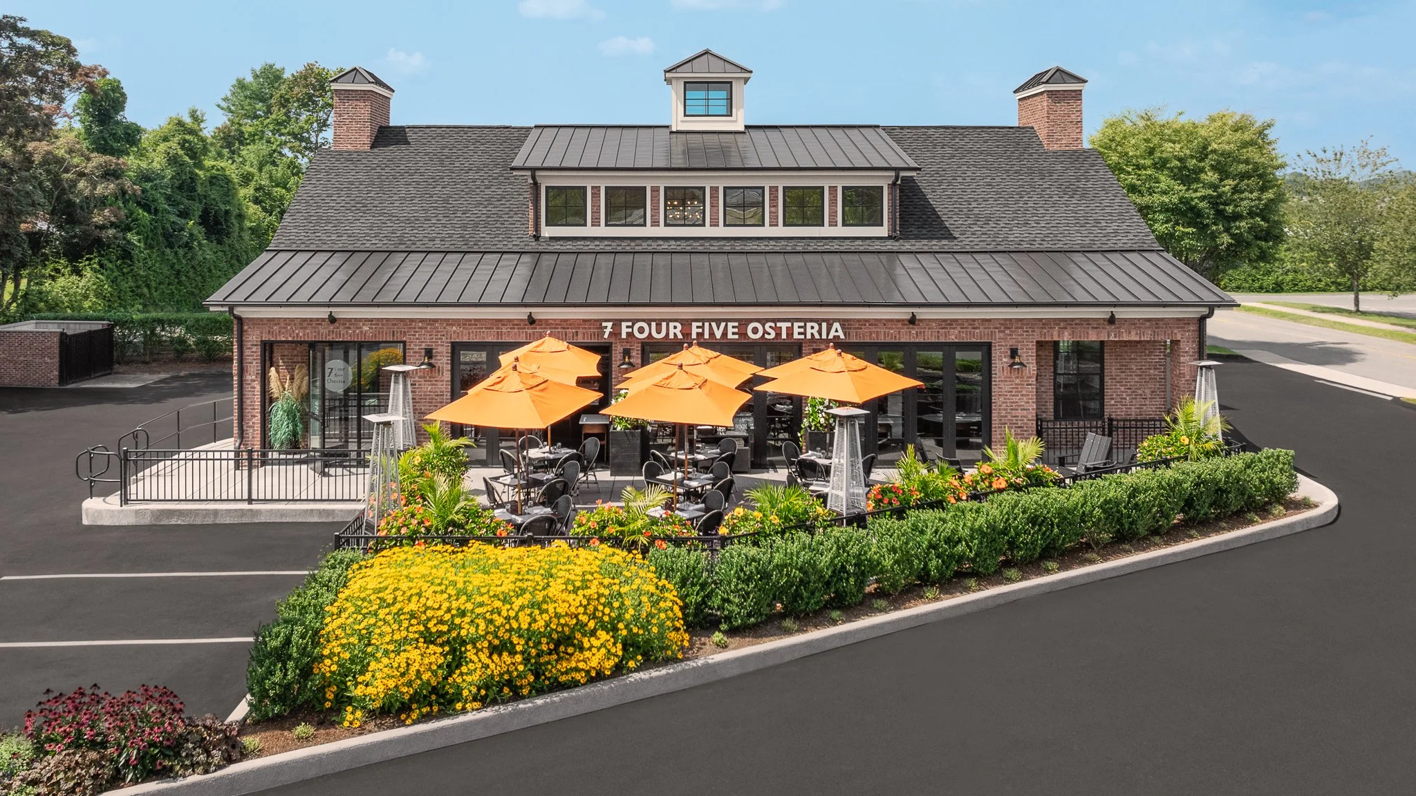 Elevated view of the restaurant front, patio umbrellas and landscaping.
