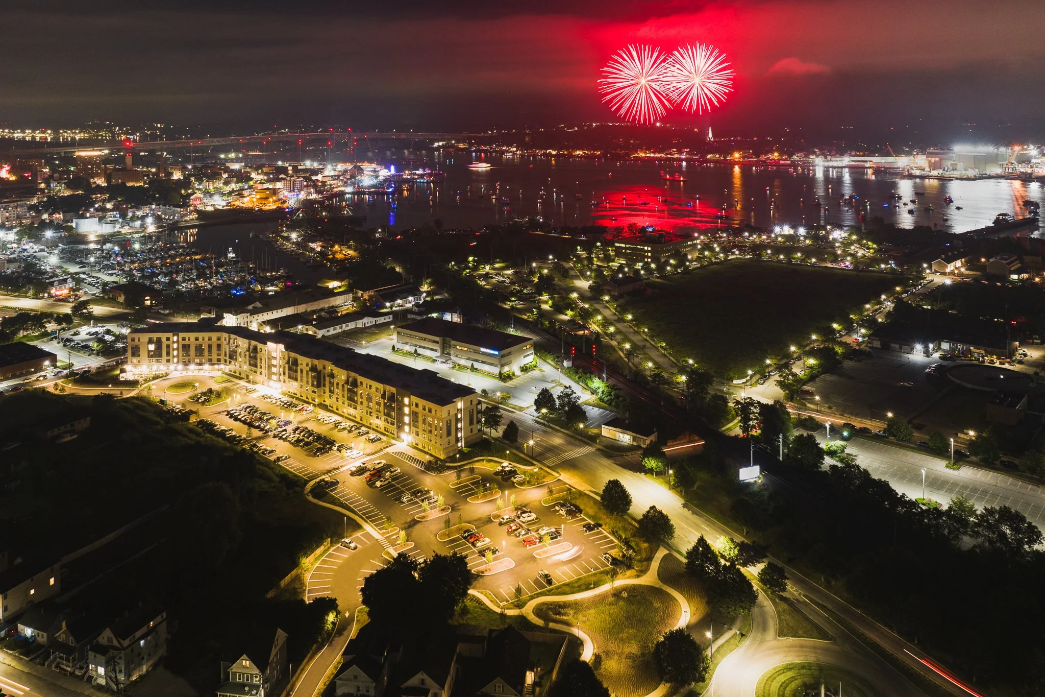 Aerial night view of Sailfest fireworks over the Thames River beyond The Beam apartments.