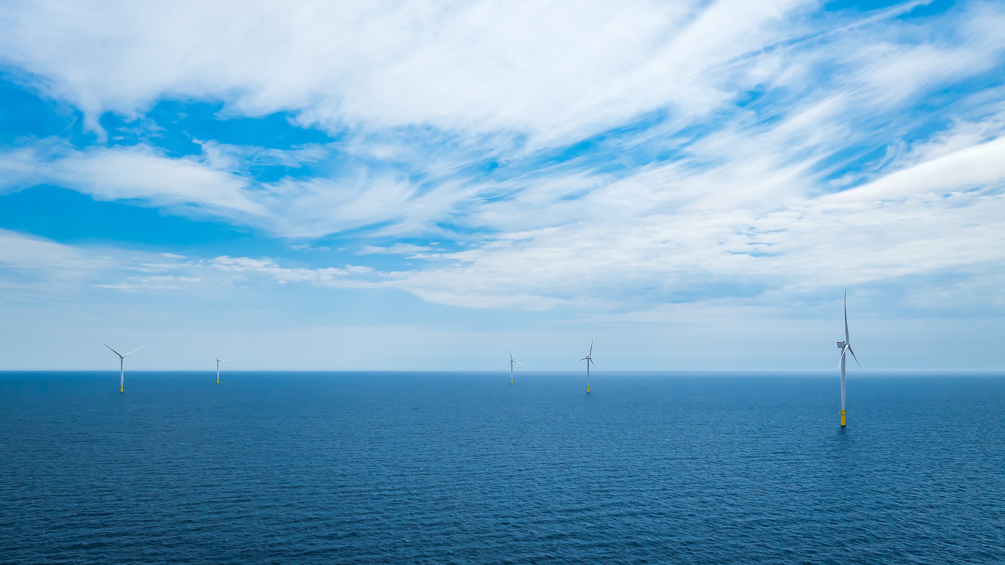 Turbines scattered along the horizon under streaks of white cloud.