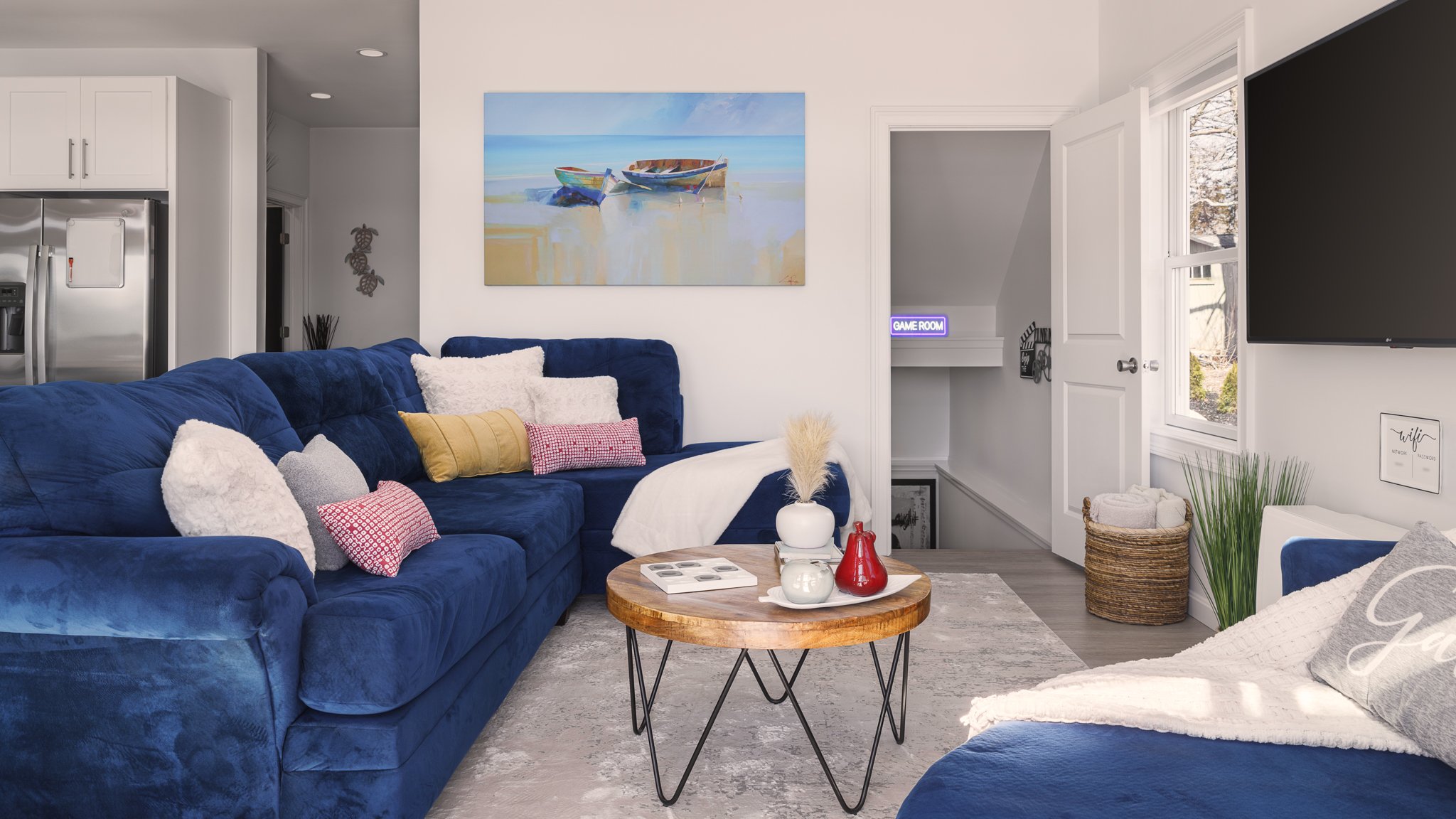 Living room with a blue sectional and a view toward the game room.
