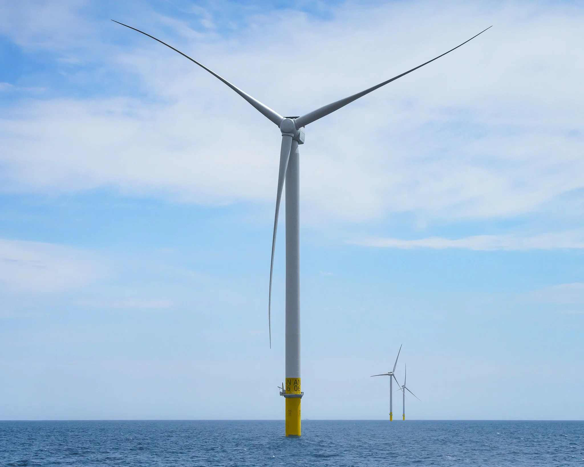 Wind turbine rotor spanning the frame, with two more turbines small in the distance.