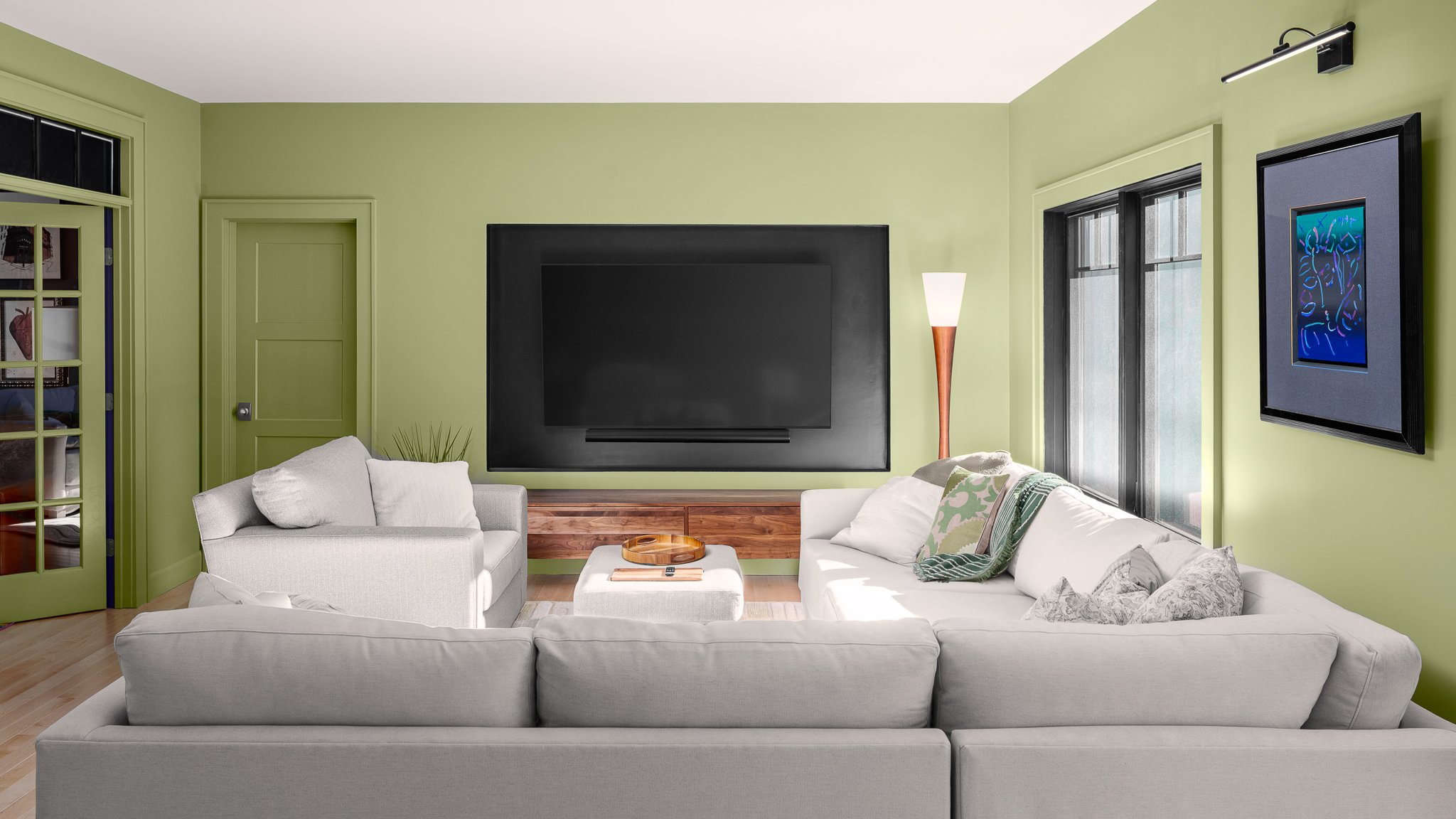 Green family room with a deep white sectional facing a wall-mounted TV.