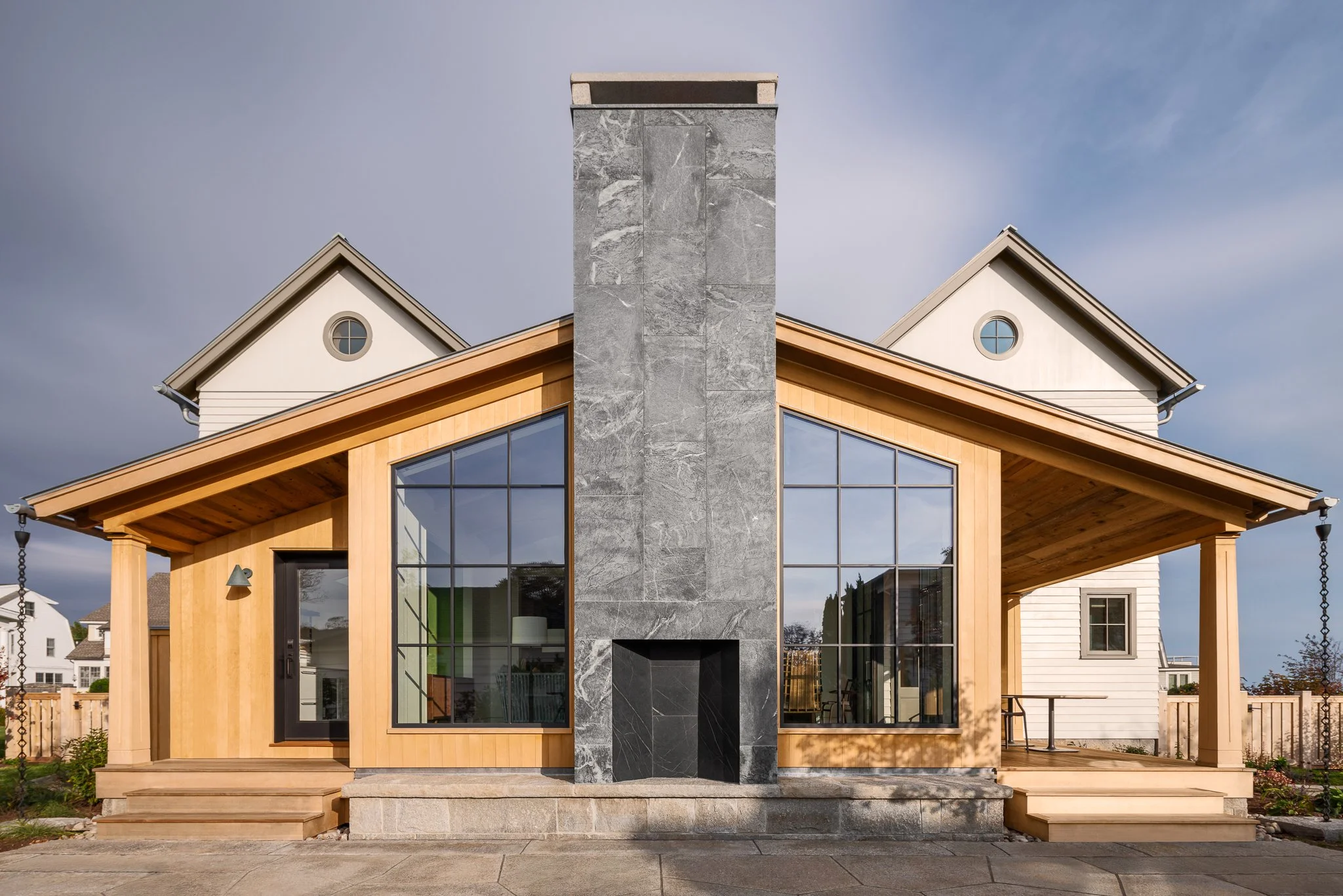 Guest house by Peggy Sullivan of Seabird Architects, framed by a central stone chimney and walls of glass in Madison, CT.