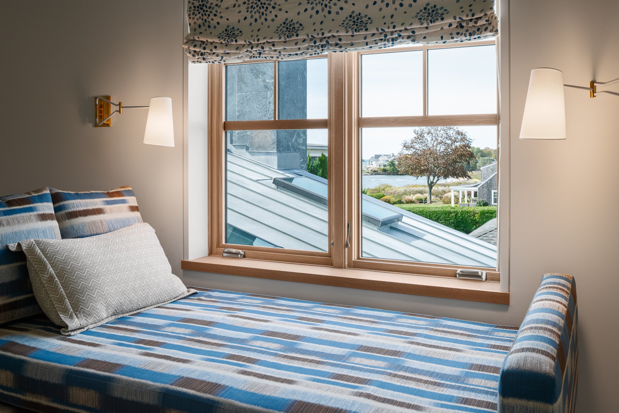 Cushioned window day bed with reading lamps and a view over the roofs to the water.