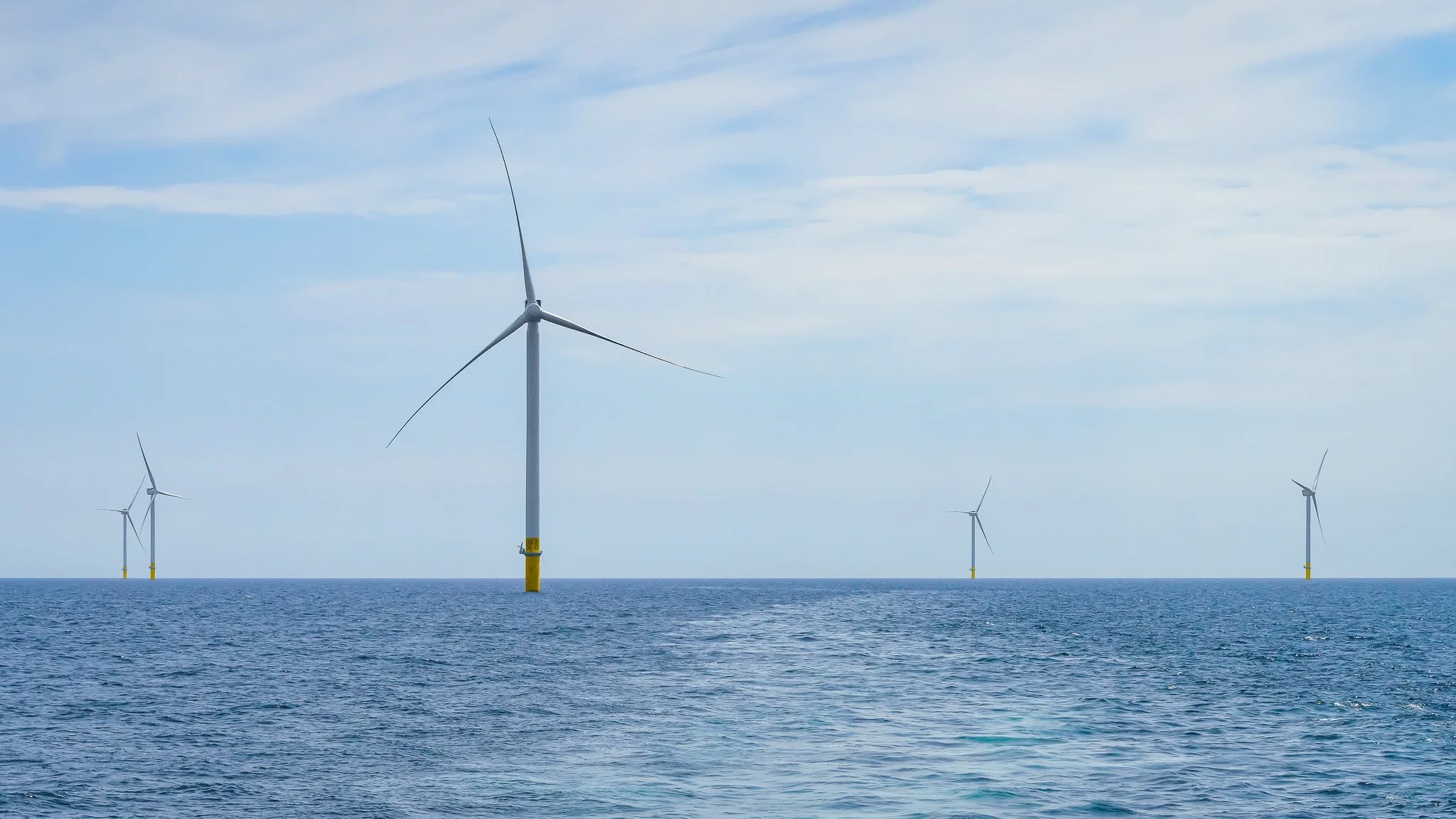 Wind turbine in calm water with four more in the distance.