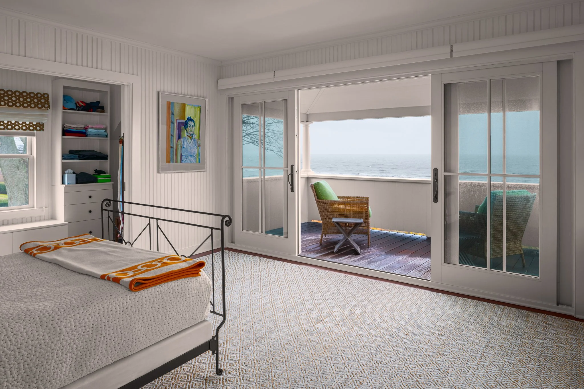 Primary bedroom opening onto a balcony above the stormy water.