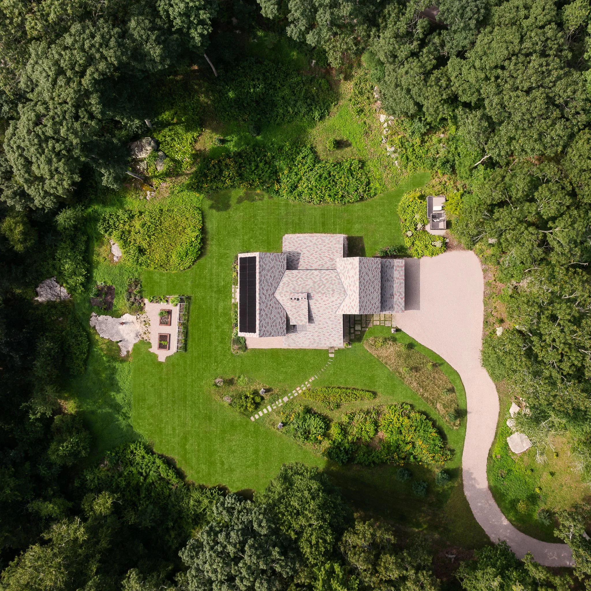Top-down aerial drone view of the home and winding driveway surrounded by woods.