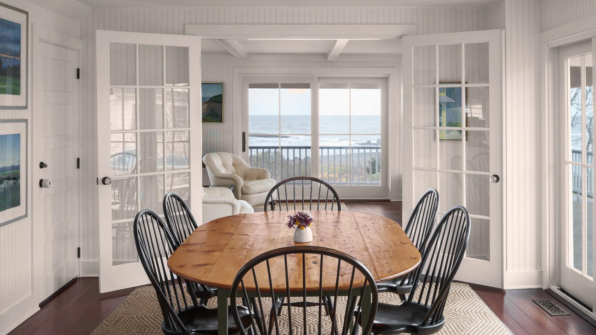 Oval dining table with Windsor chairs, French doors and water views.