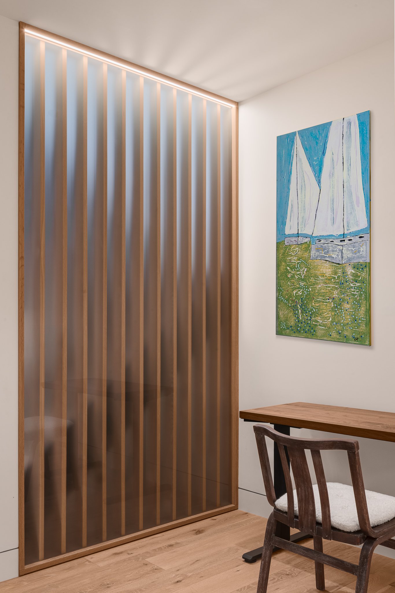 Lower-level office lit through a tall frosted glass panel.