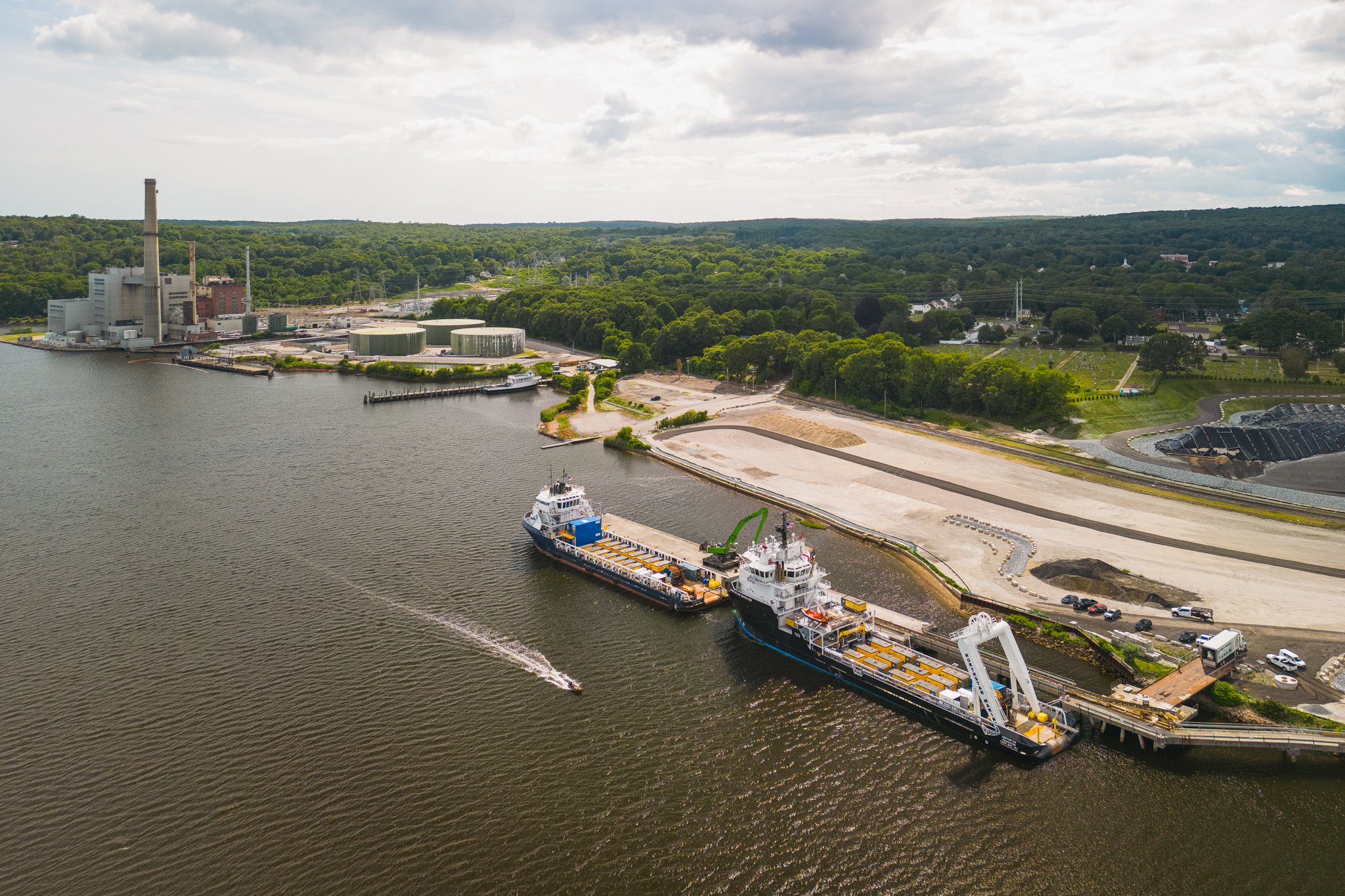 Aerial drone view of the vessels on the river with a power plant in the background.