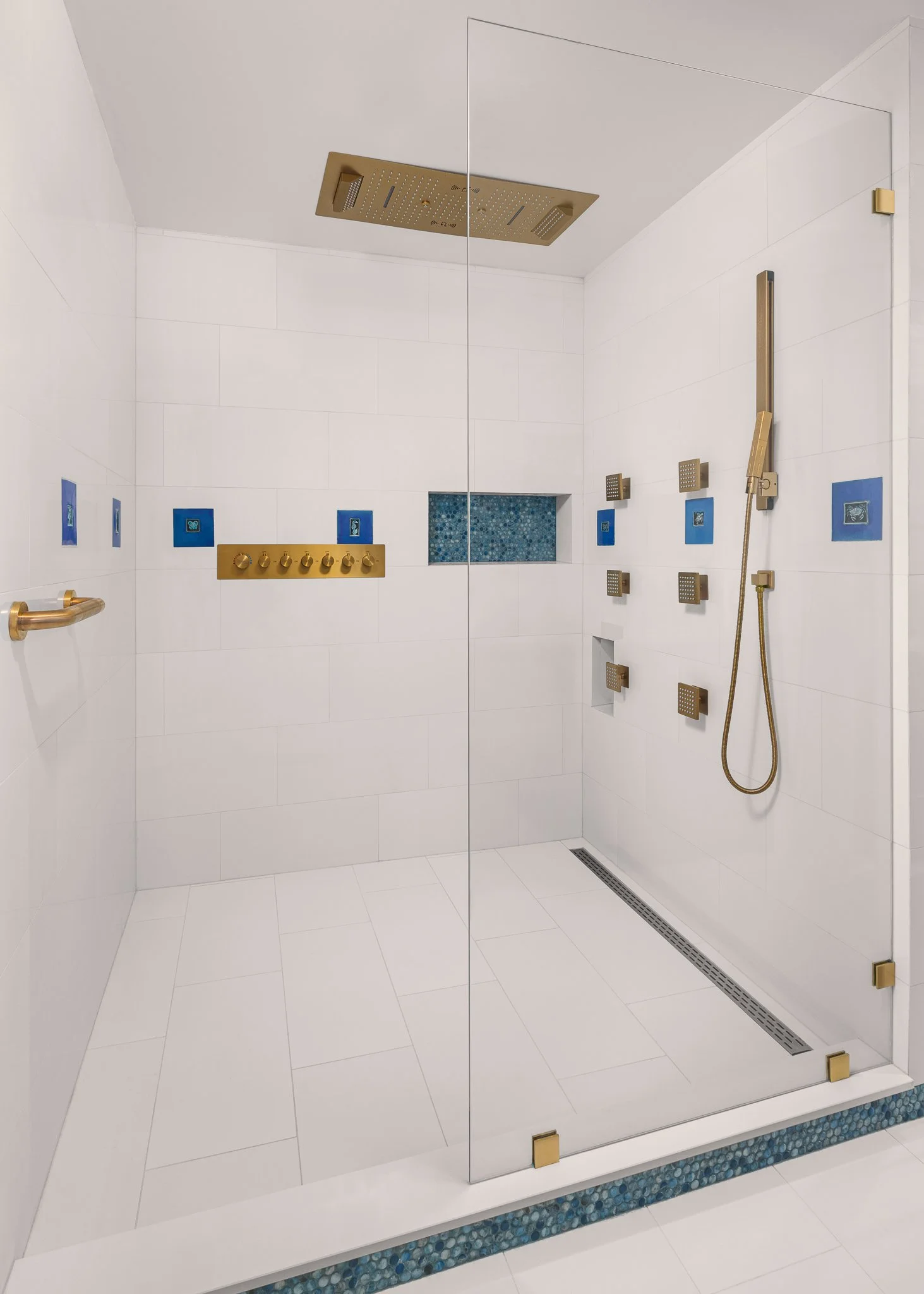 Glass walk-in shower with brass fixtures and blue accent tiles.