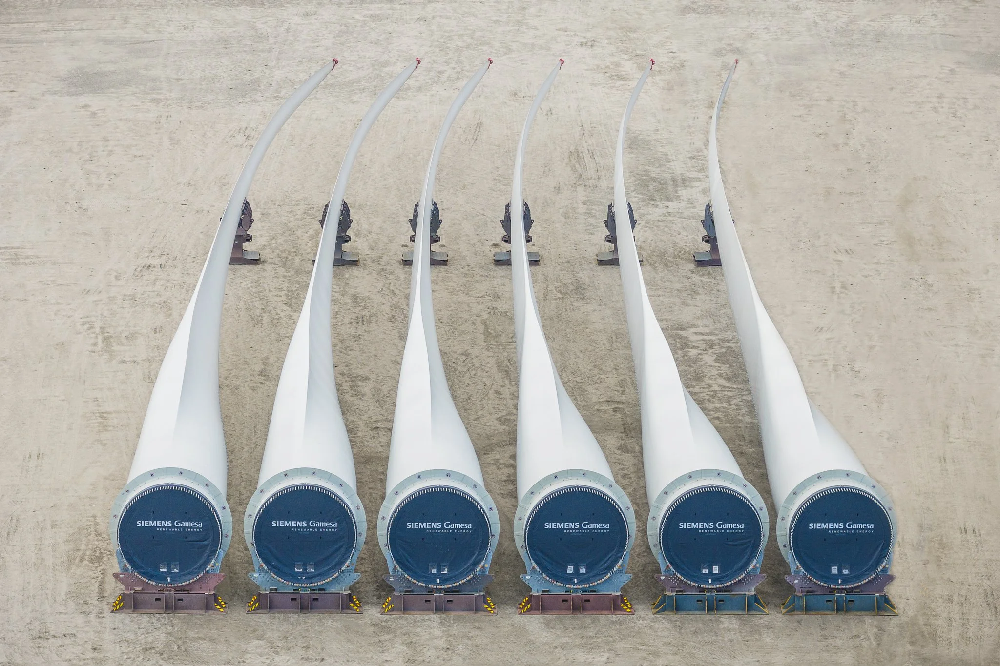 Six offshore wind turbine blades laid side by side.