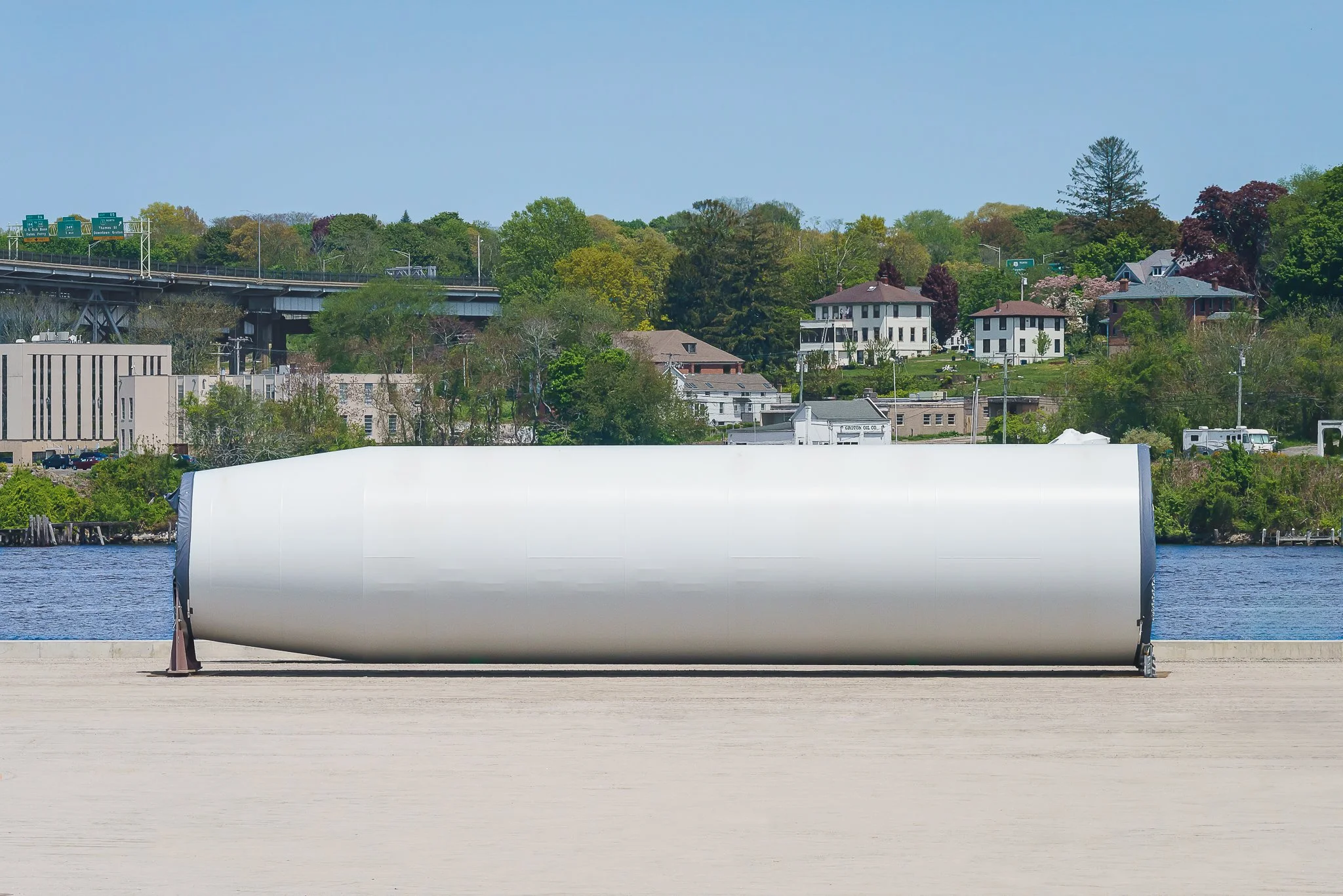 Wind turbine tower section staged at New London State Pier, with the Thames River behind.