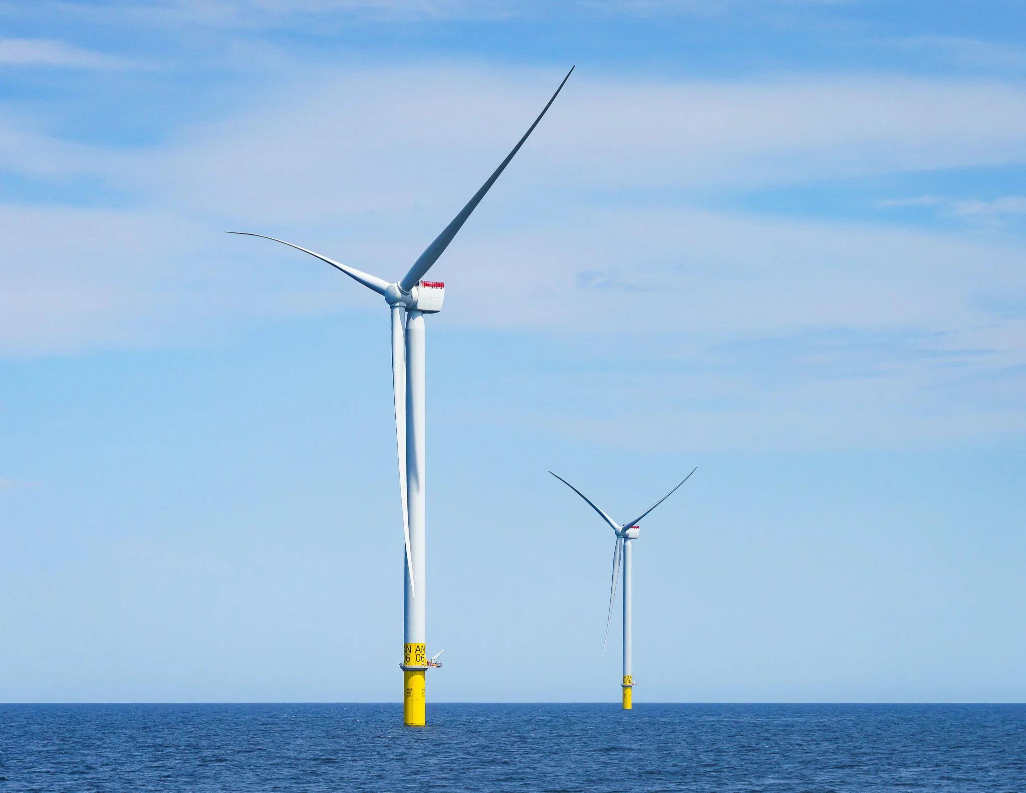 Closer view of two wind turbines, the nearer one filling much of the frame.