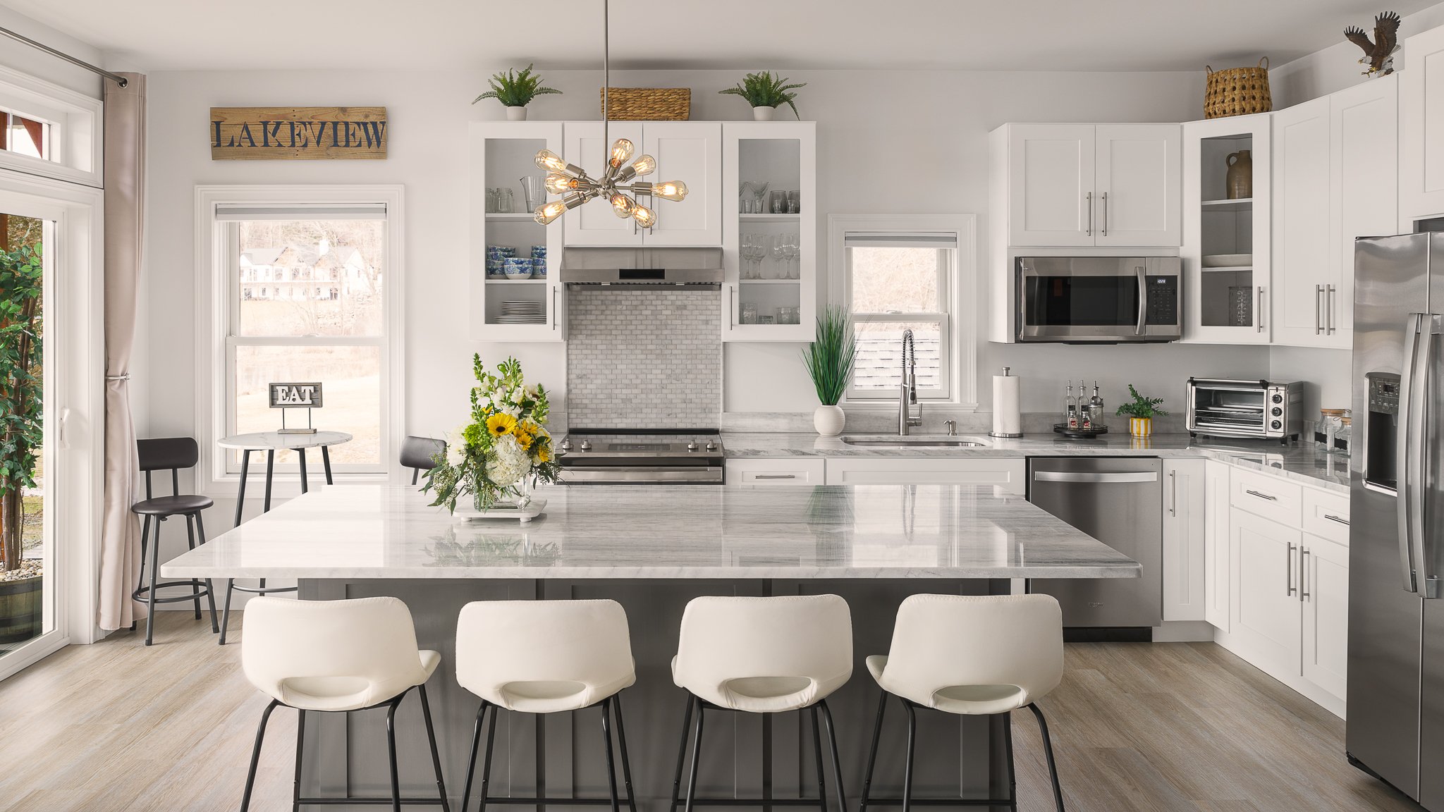 White kitchen with a large island and bar stools.
