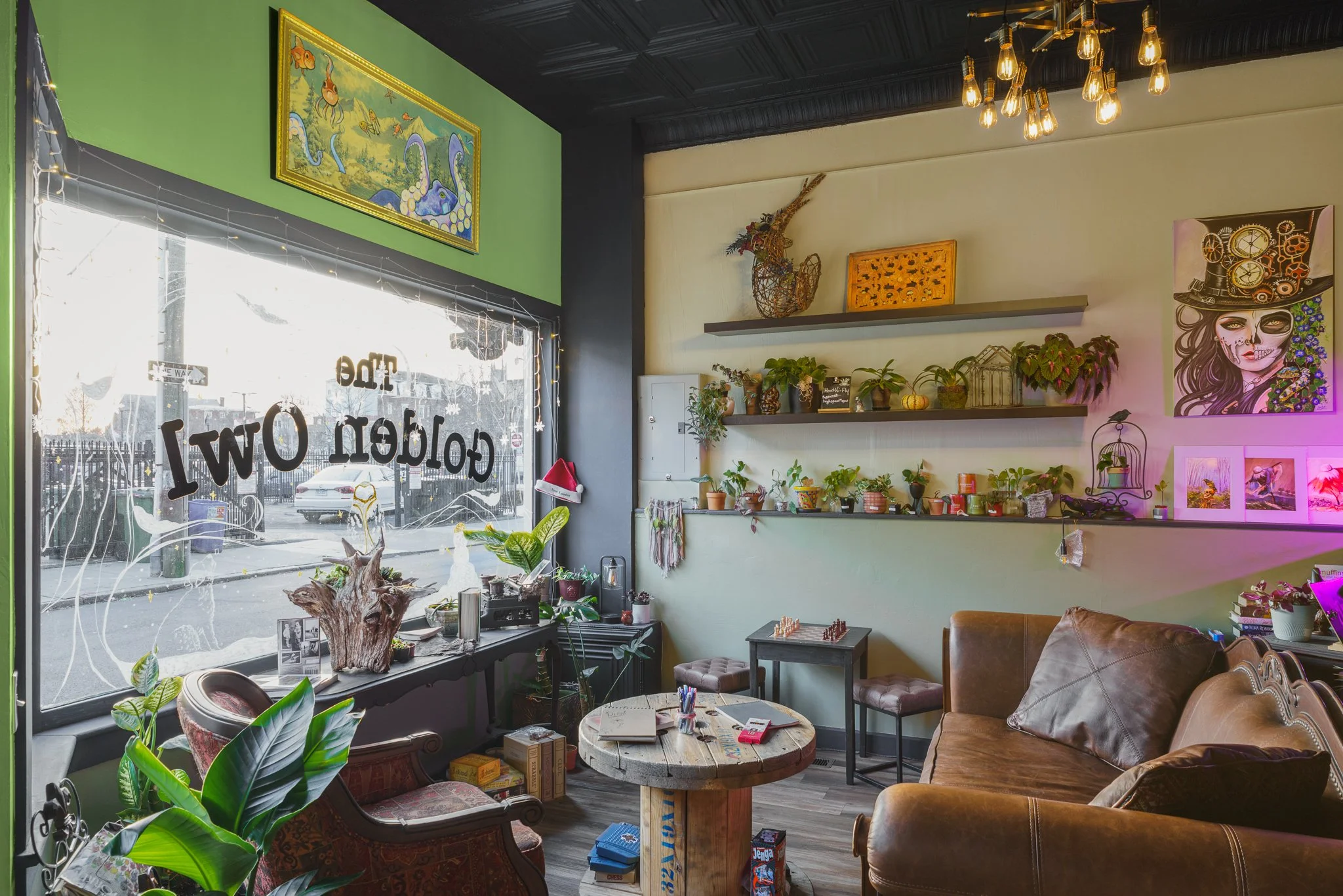 Front window seating area with a leather couch and plant shelves at The Golden Owl in New London, CT.