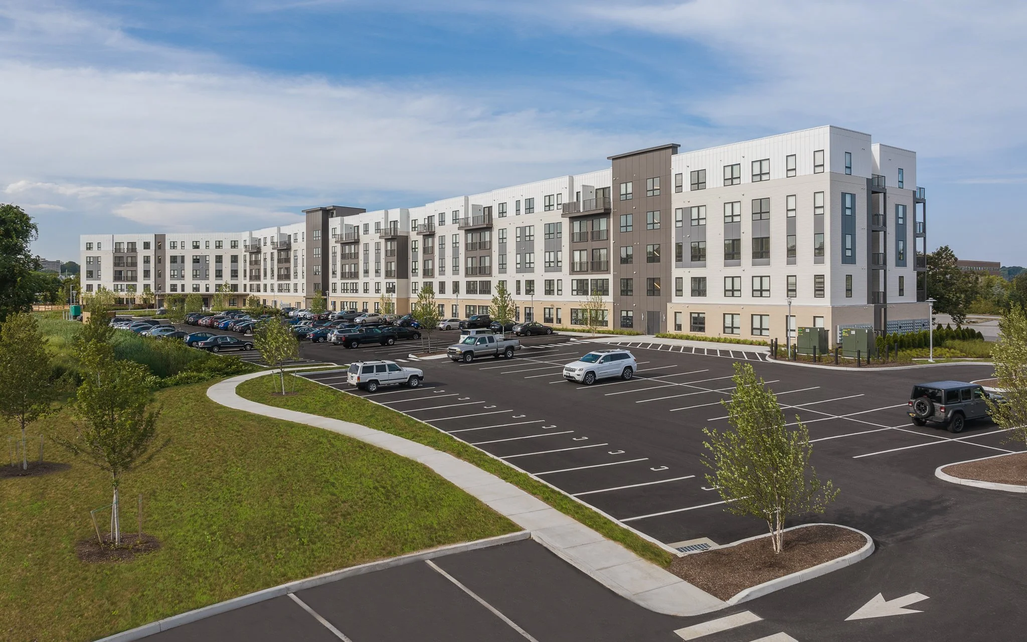 Apartment building exterior and parking lot with a curving walkway.