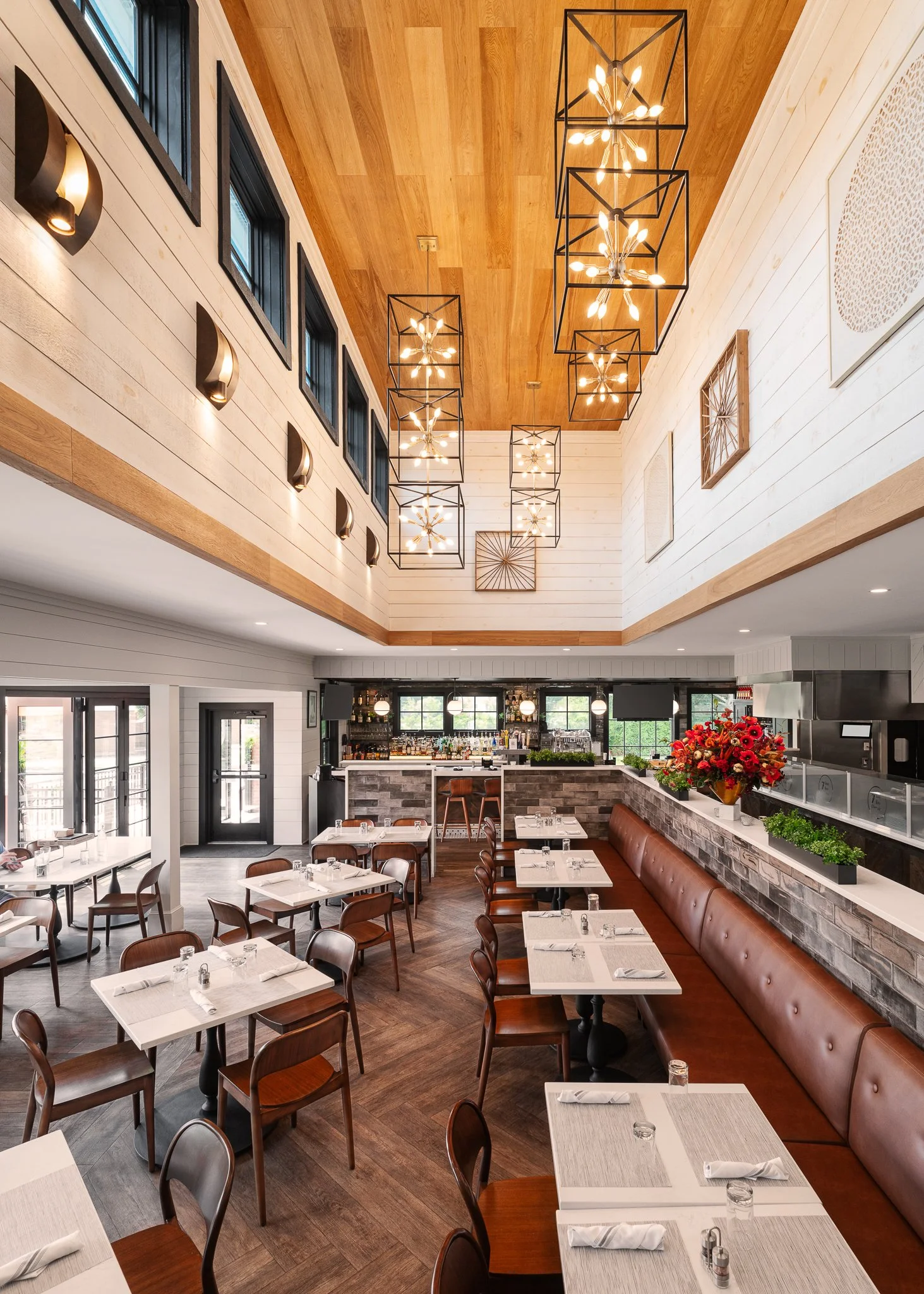 Double-height dining room at 745 Osteria with a wood plank ceiling and lantern chandeliers.