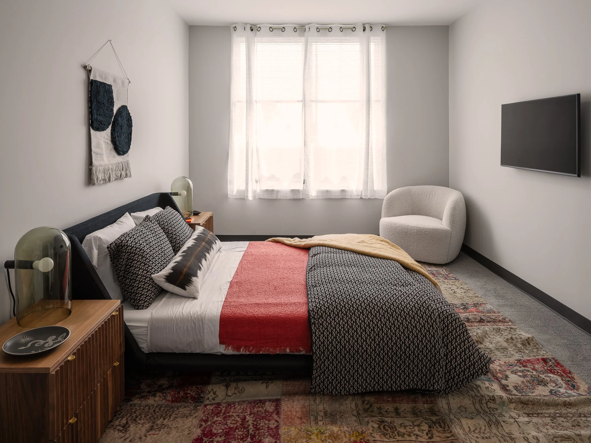 Bedroom with diffused glowing window, tv on wall, modern low bed at Cadence On Canal, New Haven, CT