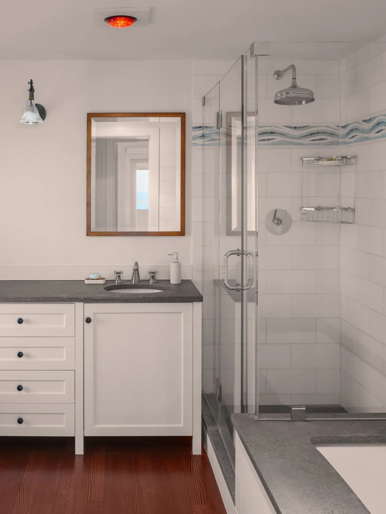Bathroom with a white vanity, glass shower and a red heat lamp overhead.