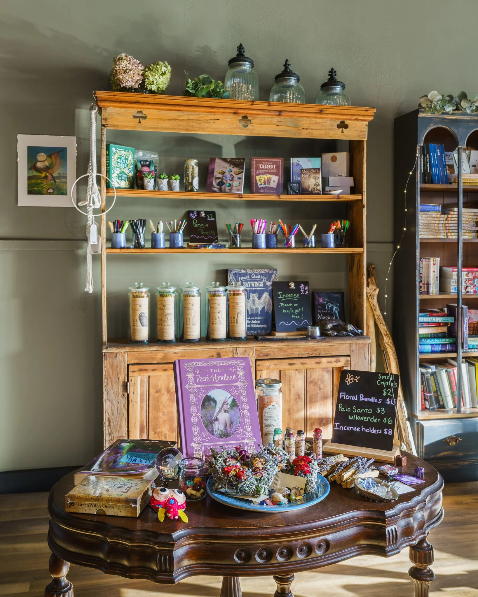 Wooden hutch displaying floral bundles, incense and apothecary jars.