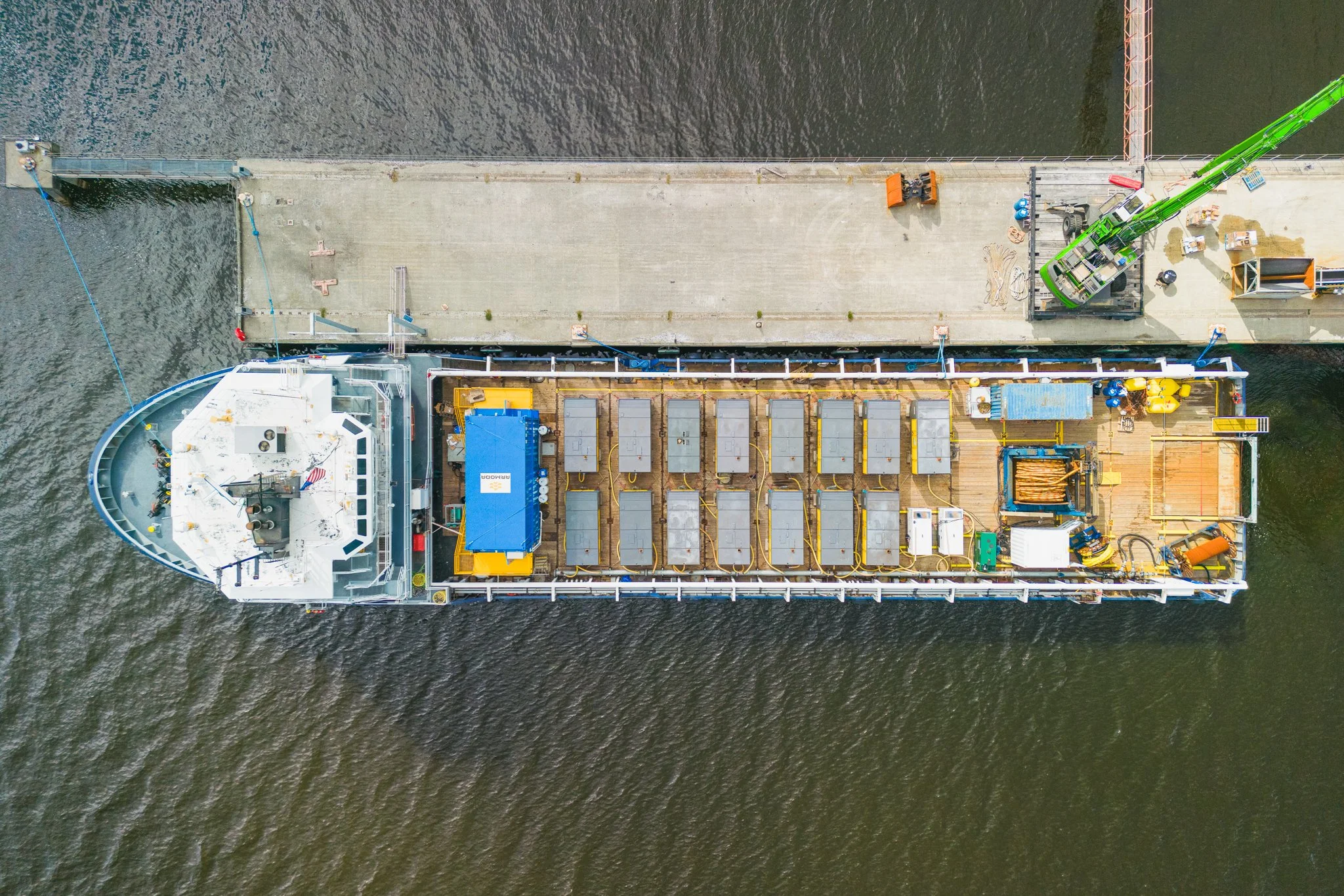 Top-down aerial drone view of a vessel's deck and equipment at the dock.