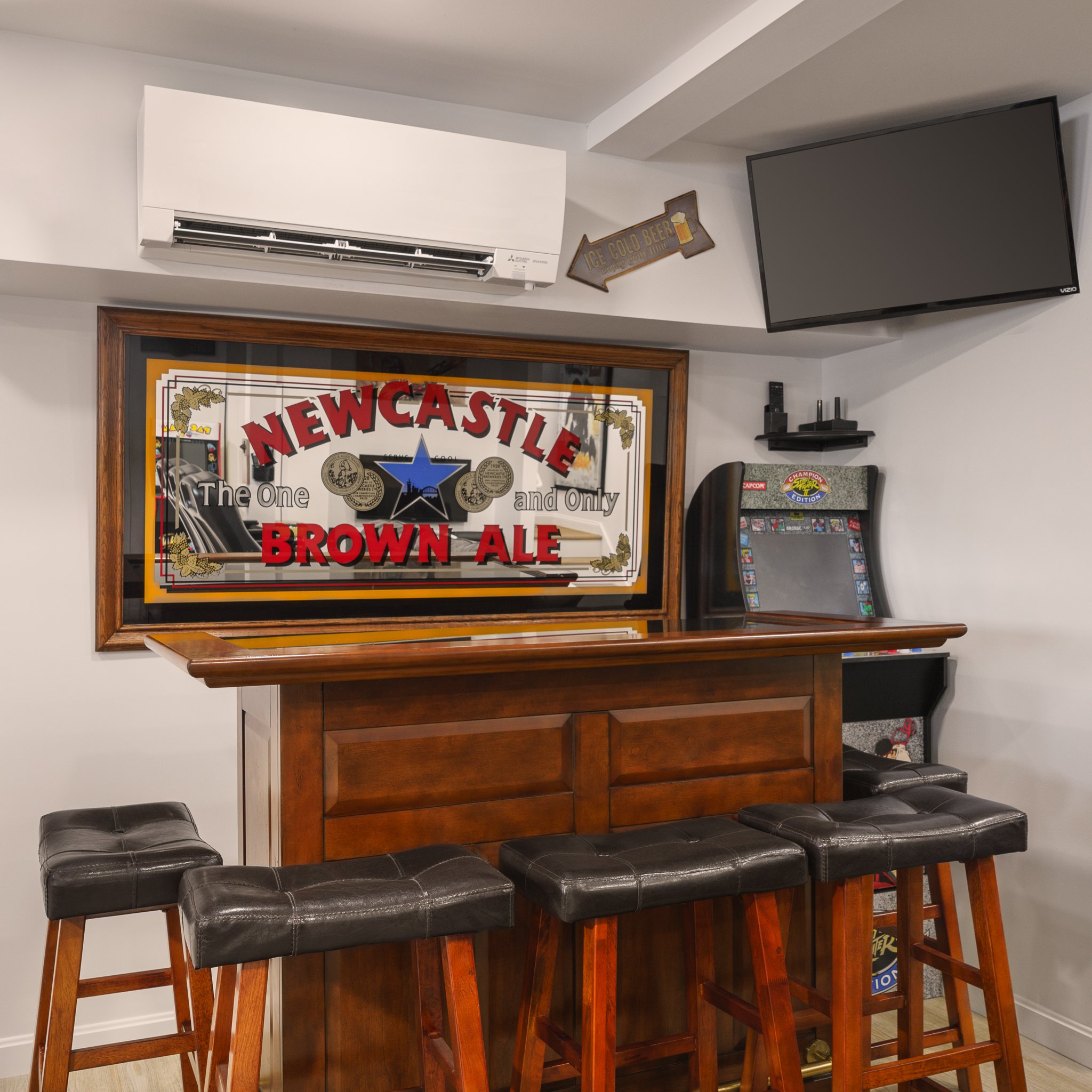 Basement bar with a Newcastle Brown Ale mirror and leather stools.