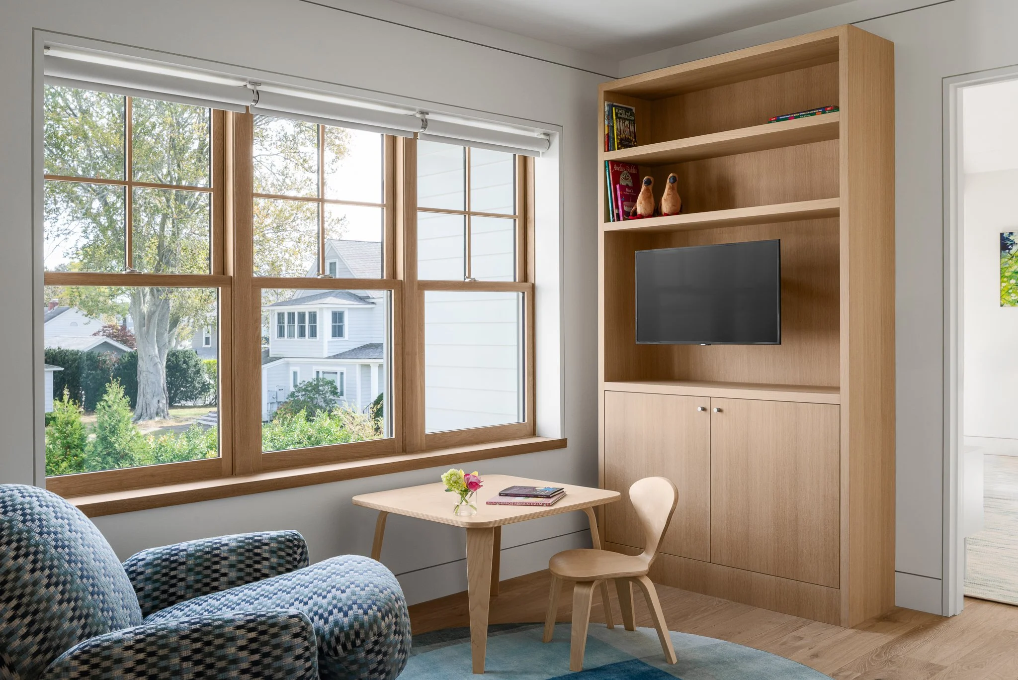 Built-in bookshelf and window nook with a child-sized table and chairs in a guest house by Peggy Sullivan of Seabird Architects in Madison, CT.
