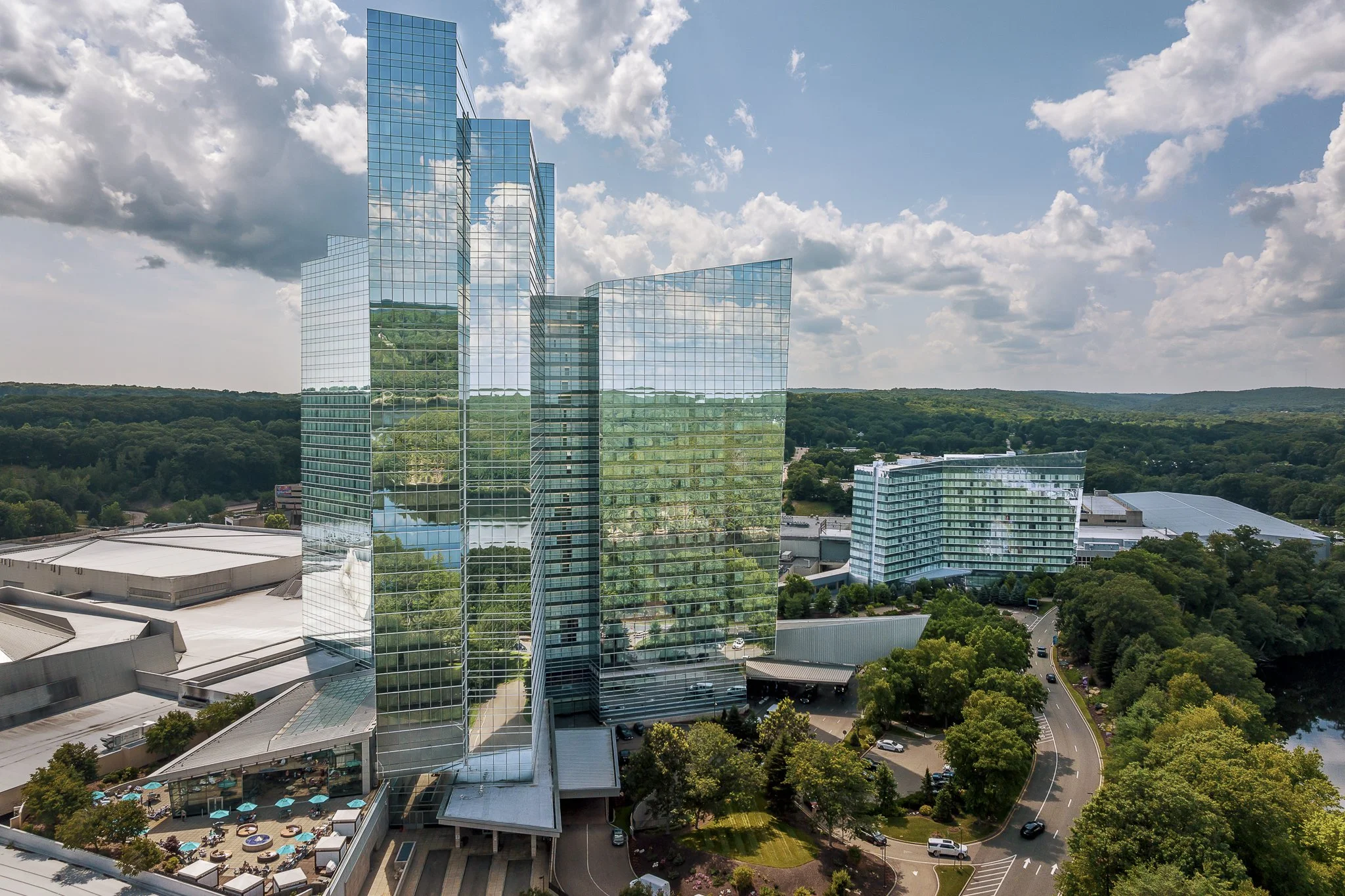 Mohegan Sun Sky and Earth hotel towers, reflective glass windows, lobby entrance, partly cloudy blue sky, Uncasville, CT