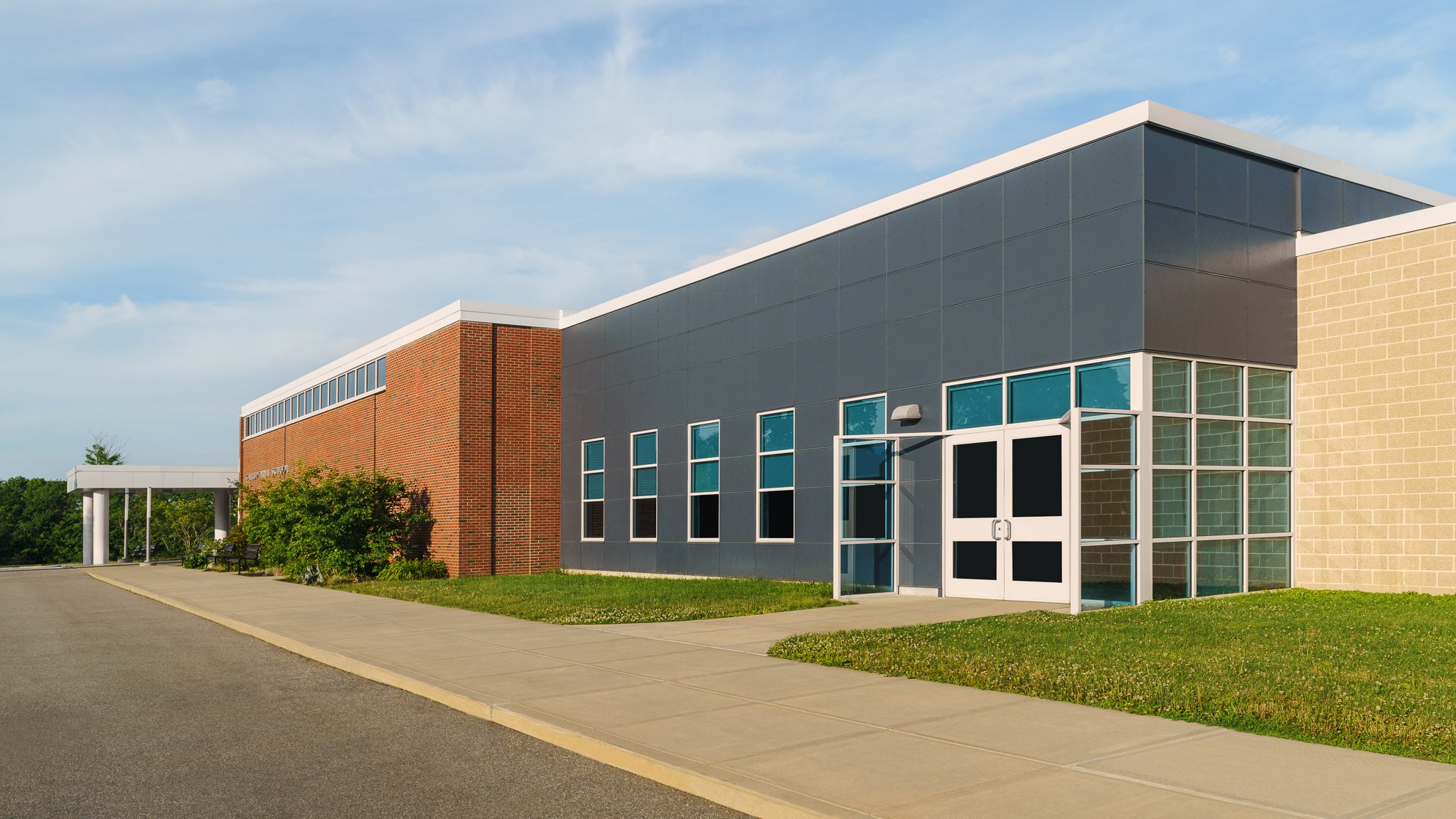 Side entrance where the gray panel facade meets red brick.
