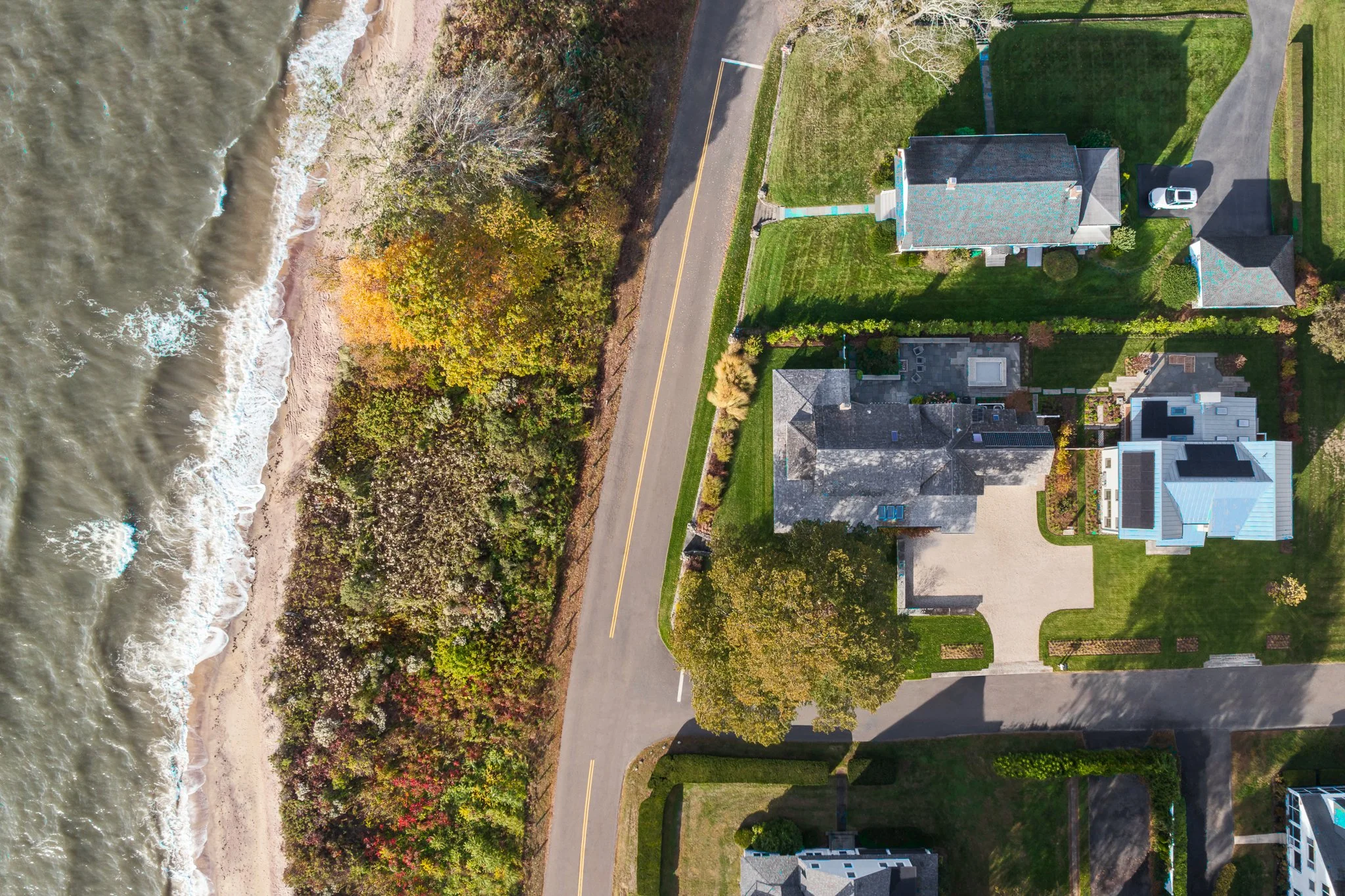 Top-down aerial drone view showing the compound between the road and the beach.