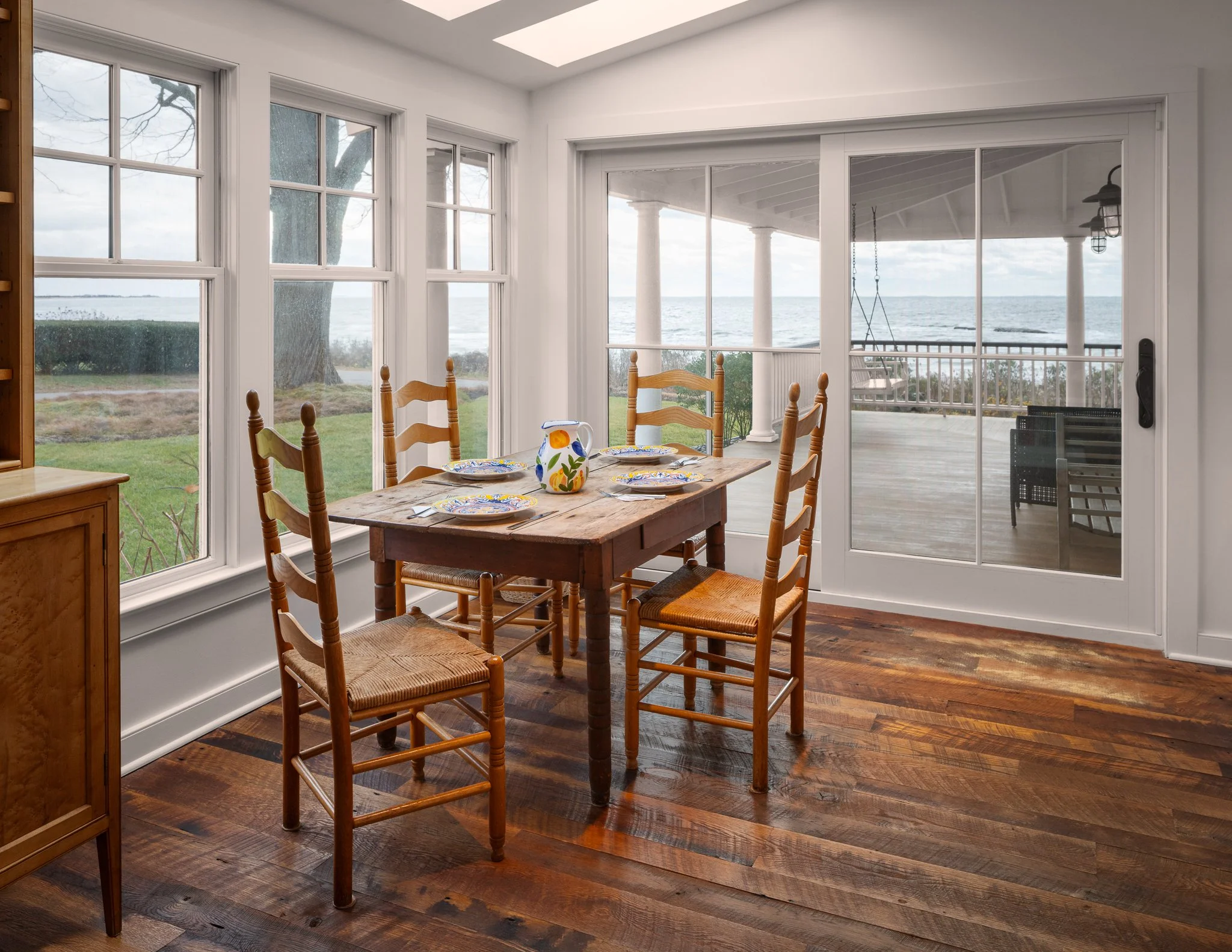 Breakfast table in a window bay facing a stormy Long Island Sound, in a home by Peggy Sullivan of Seabird Architects in Madison, CT.