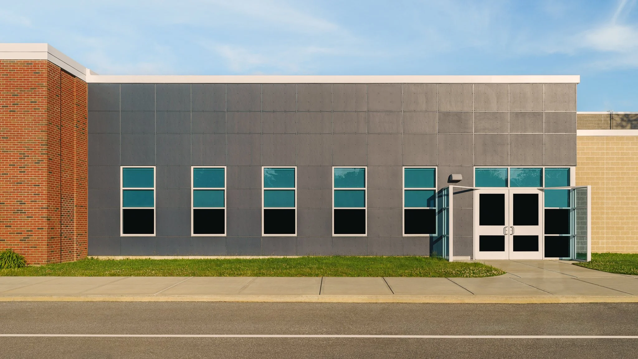 Gray panel facade with blue-trimmed windows and entry doors.