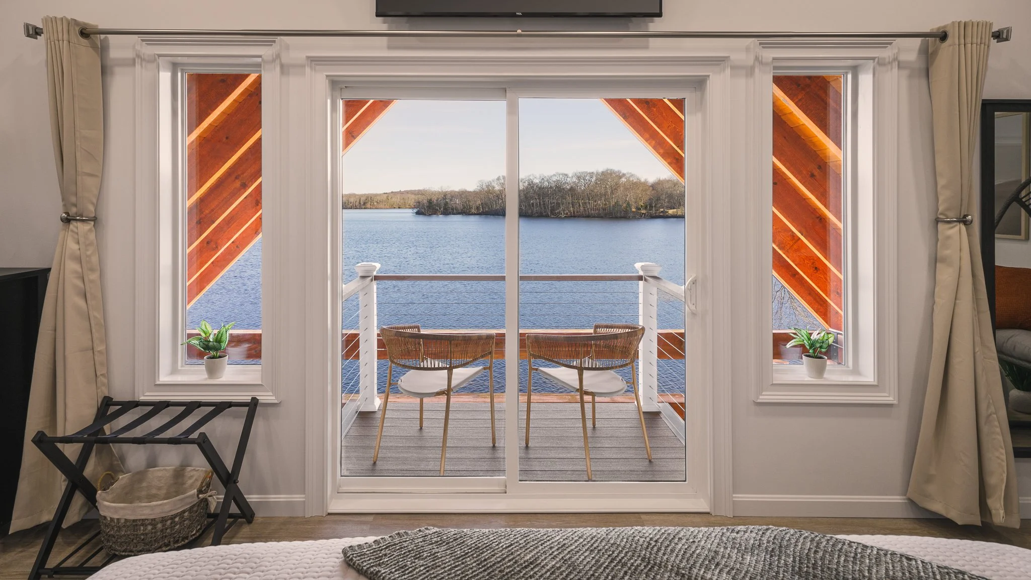 Bedroom balcony doors opening to a lake view.