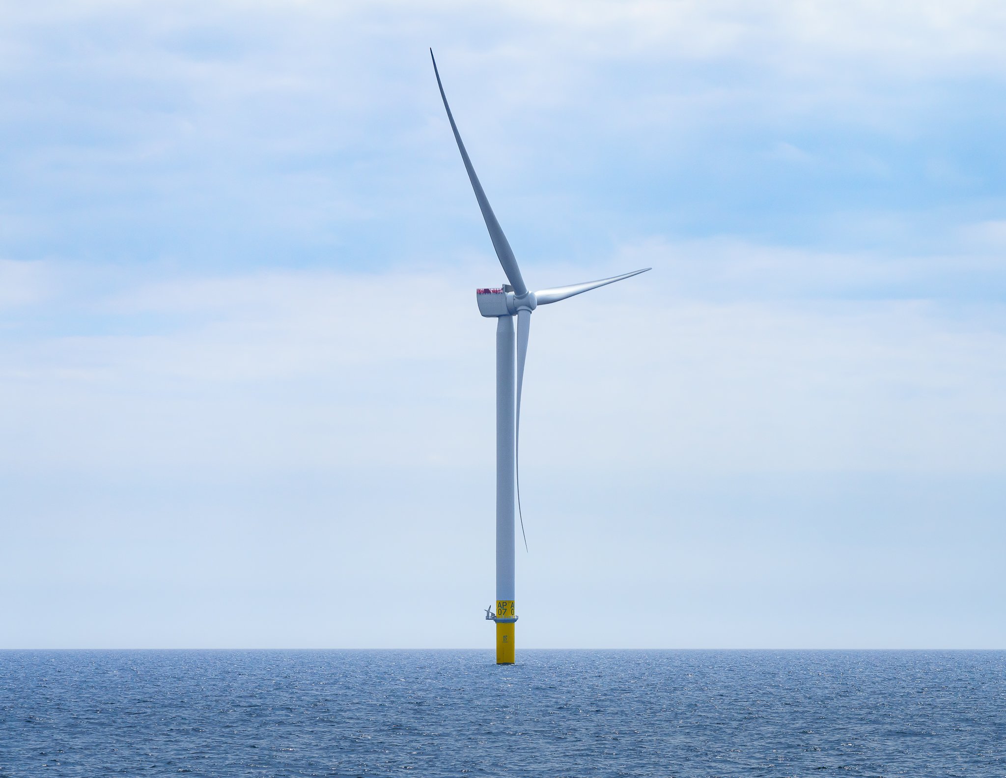 Wind turbine seen from the side under a soft, overcast sky.