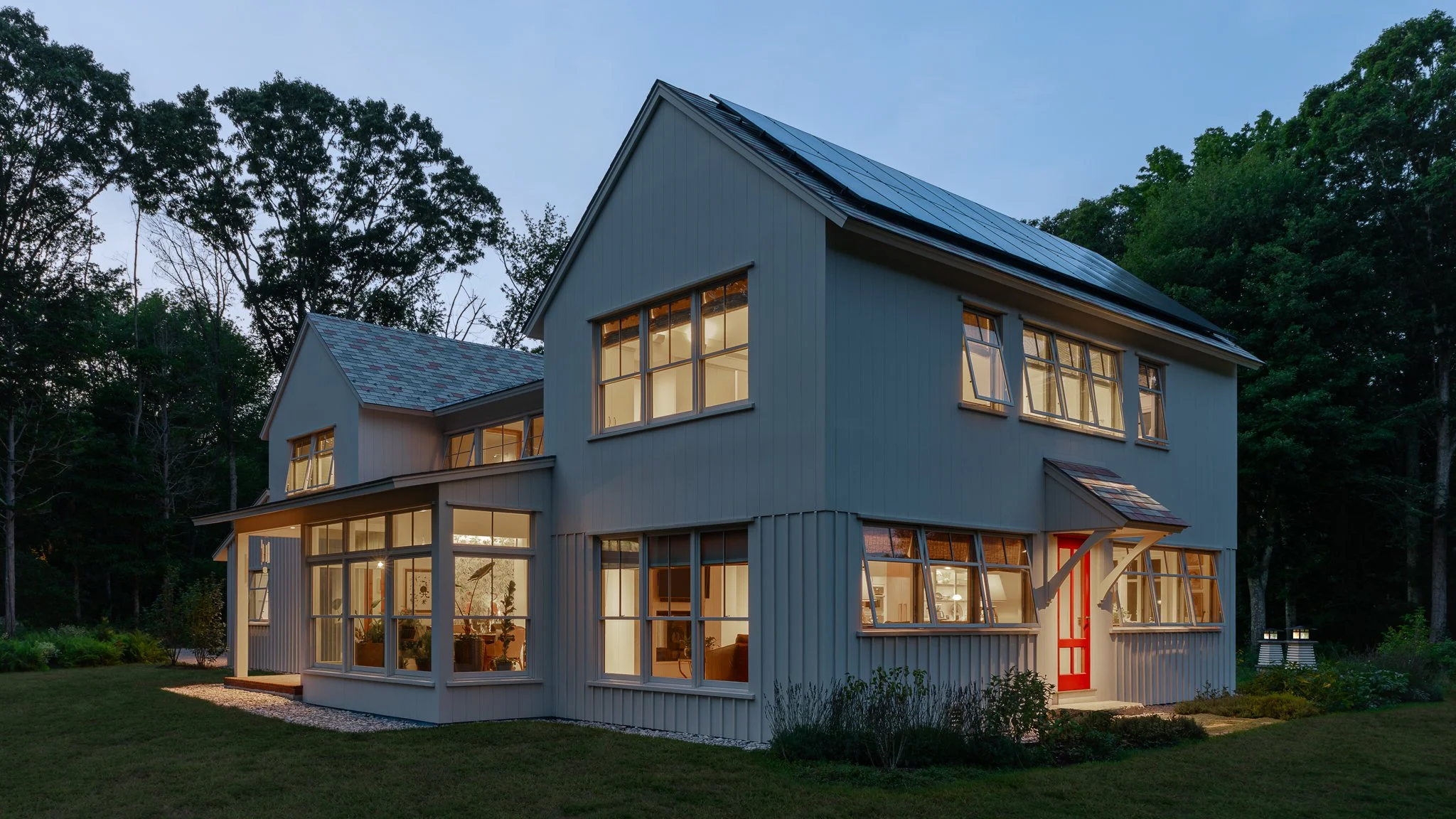 Architect's home by Michael McKinley glowing at twilight among the trees in North Stonington, CT.