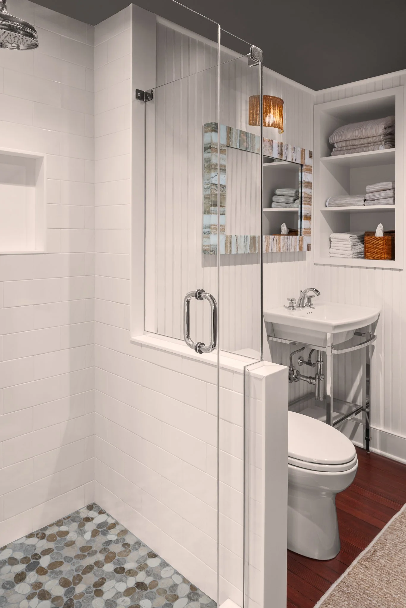Shower with a pebble tile floor next to the sink and toilet.