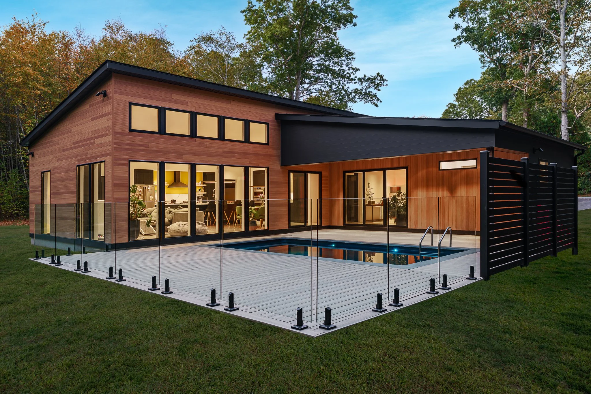 Modern home with a glass-fenced pool glowing at twilight, built by ICOR Building & Remodeling in North Stonington, CT.