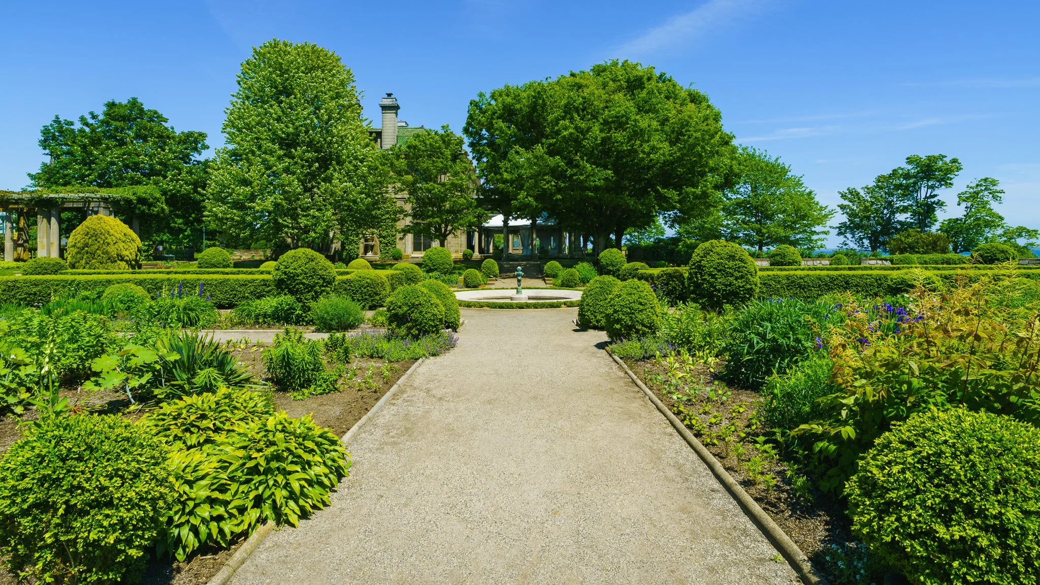 Gravel path running through manicured shrubs and flower beds in the formal gardens.