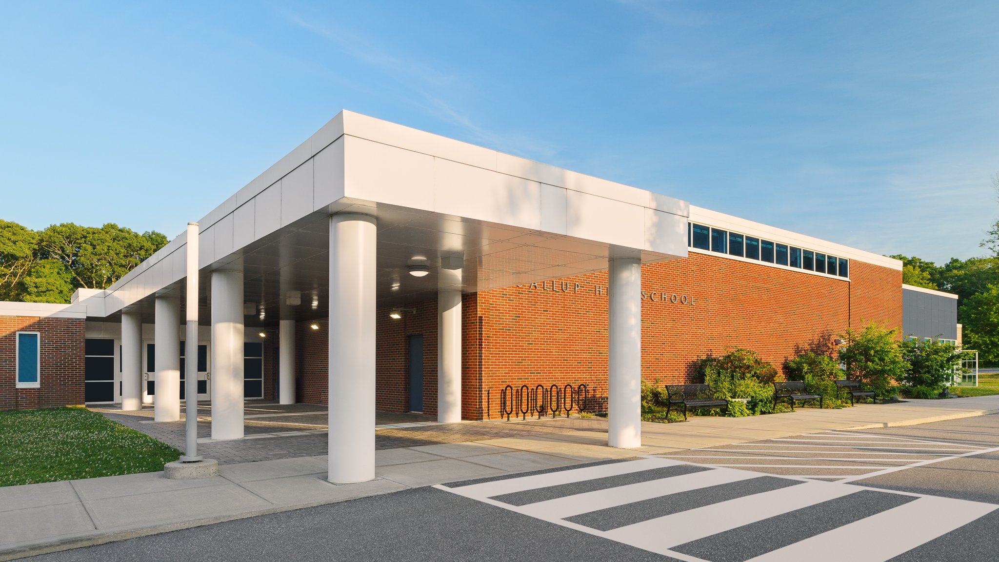 Covered main entrance of Gallup Hill School with white columns and a crosswalk.
