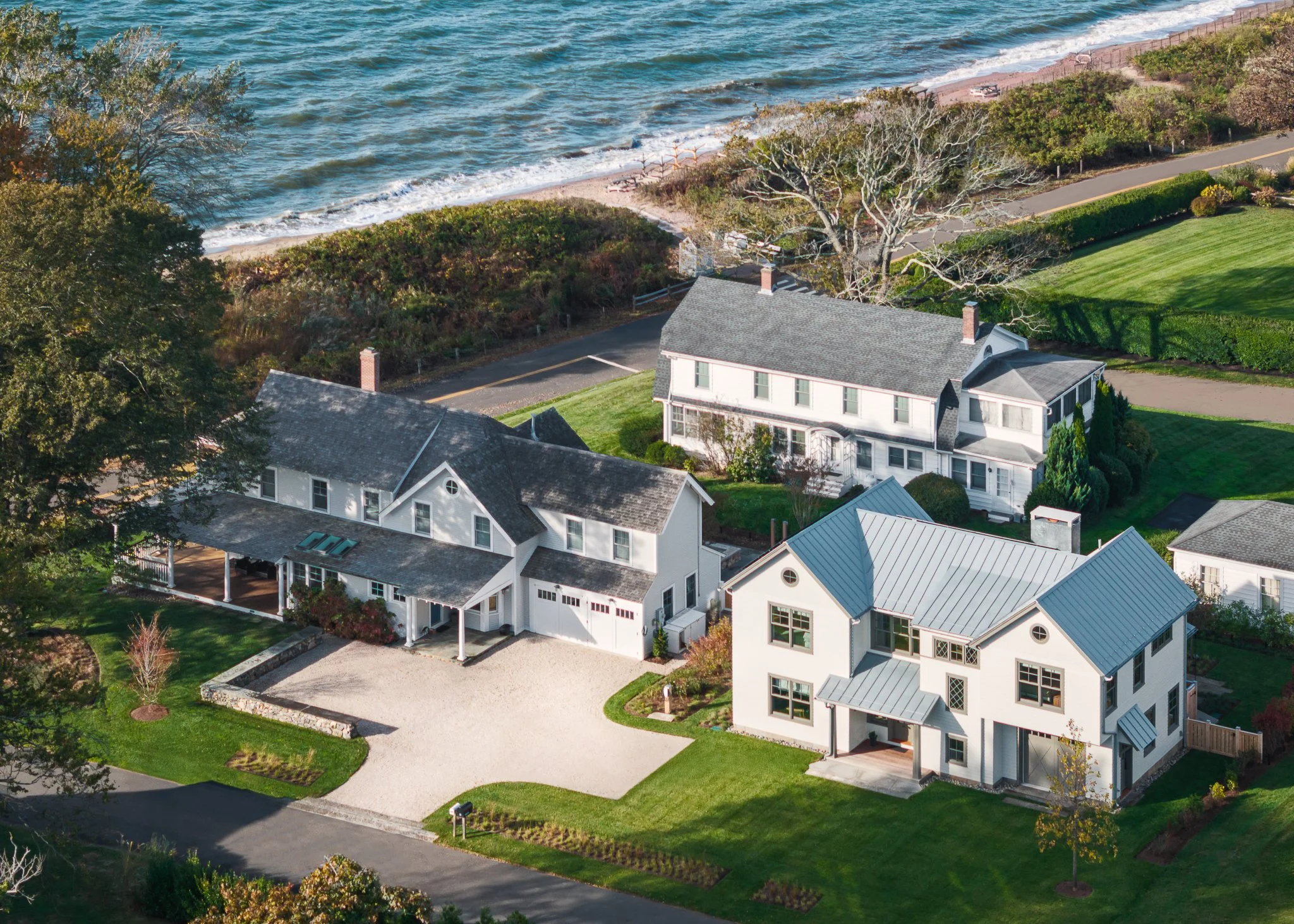 Aerial drone view of a shoreline compound with a main house and guest house above Long Island Sound.